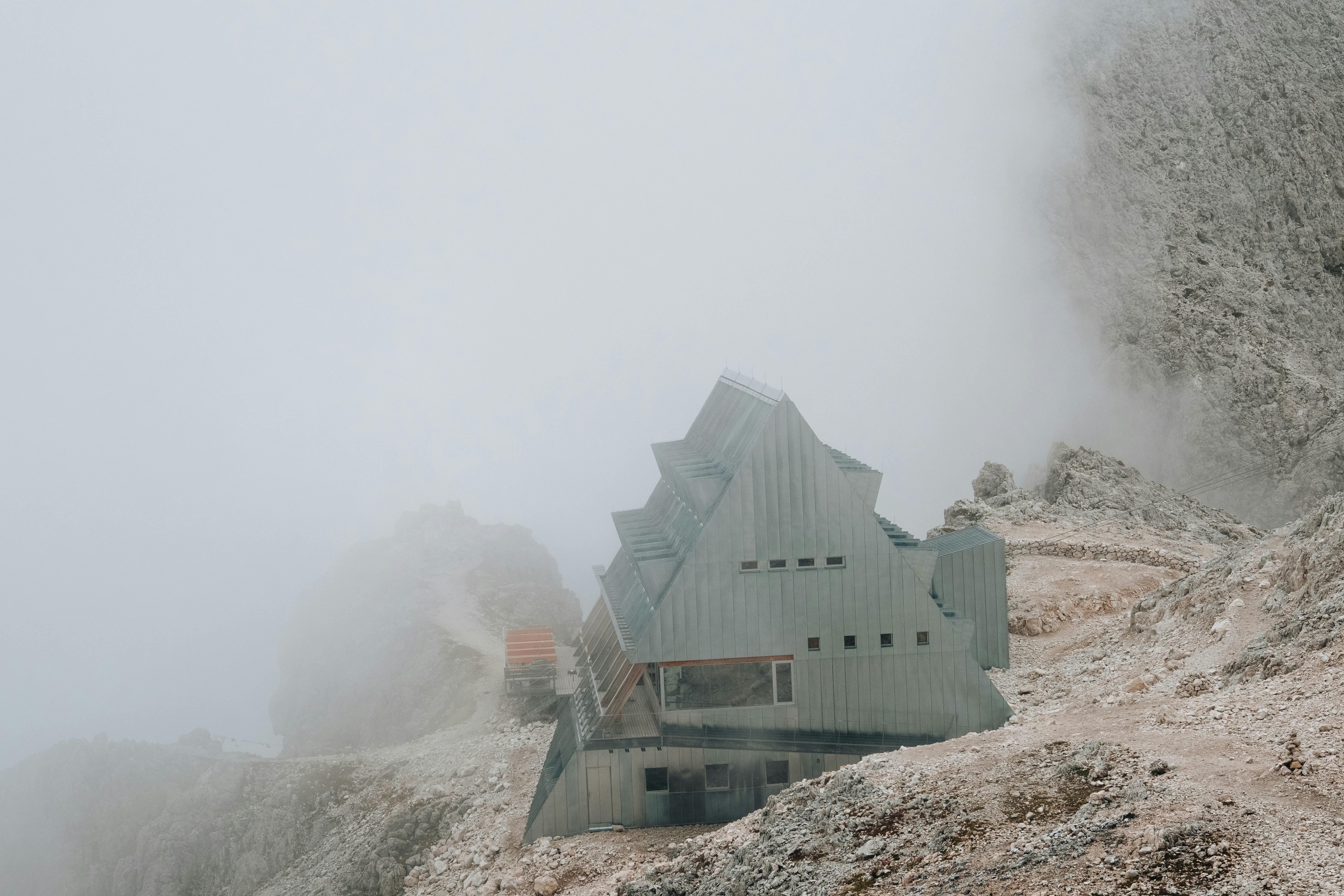Uma cabana de montanha de metal moderna aninhada em uma encosta rochosa em uma névoa densa