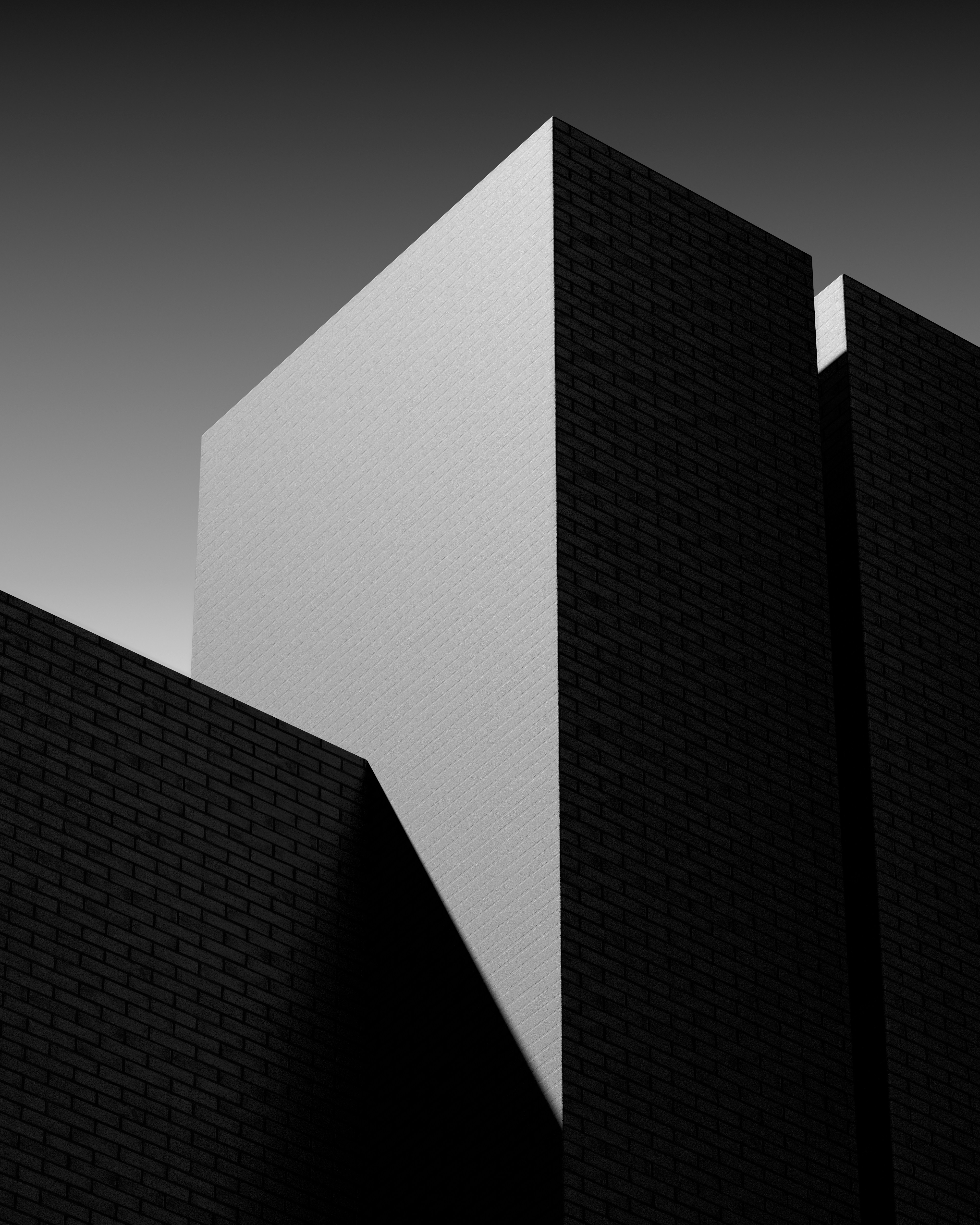 Geometric black brick walls meeting at sharp angles under a bright light