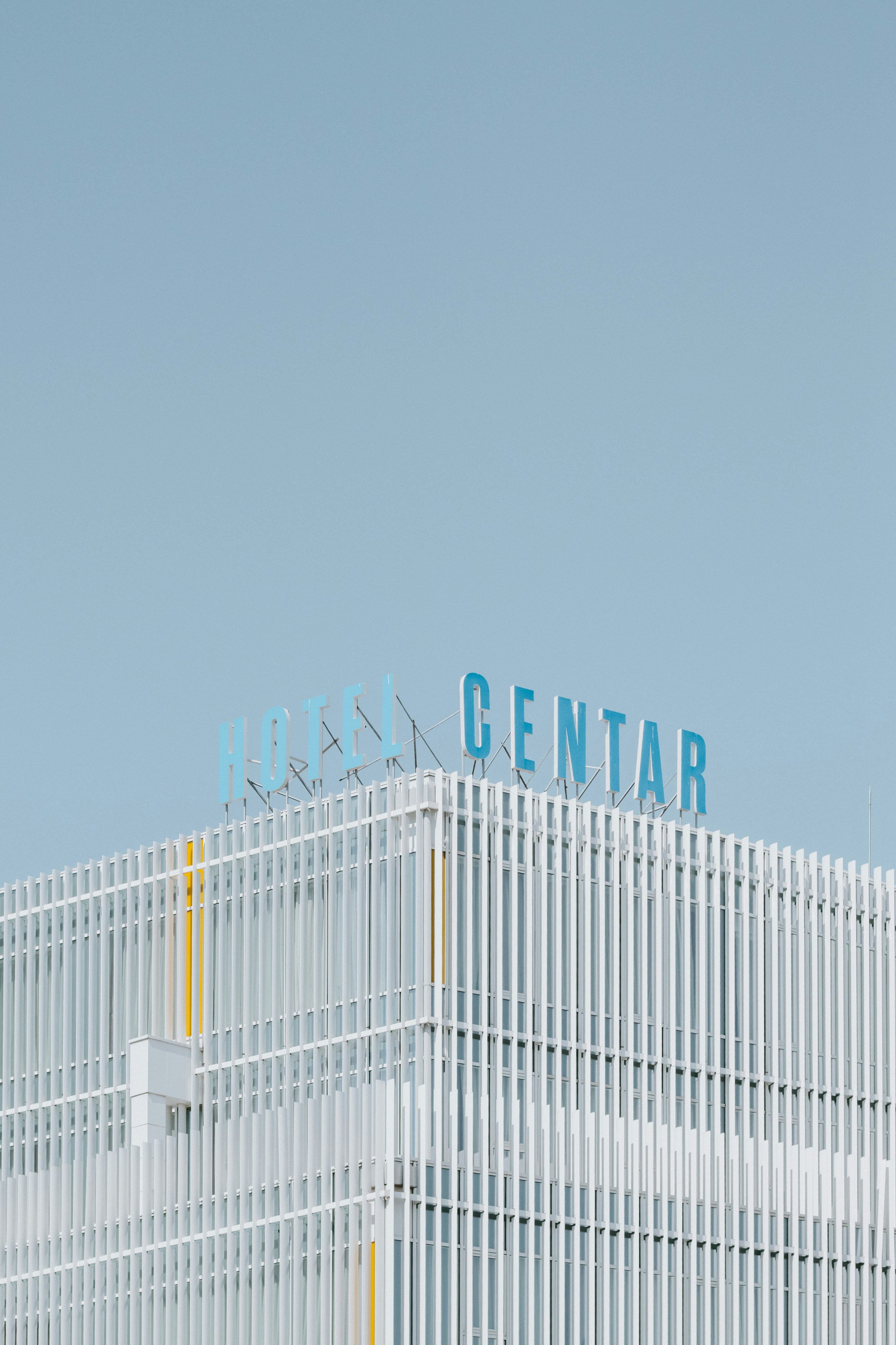 A sign reading "HOTEL CENTAR" atop a modern building with white vertical louvers