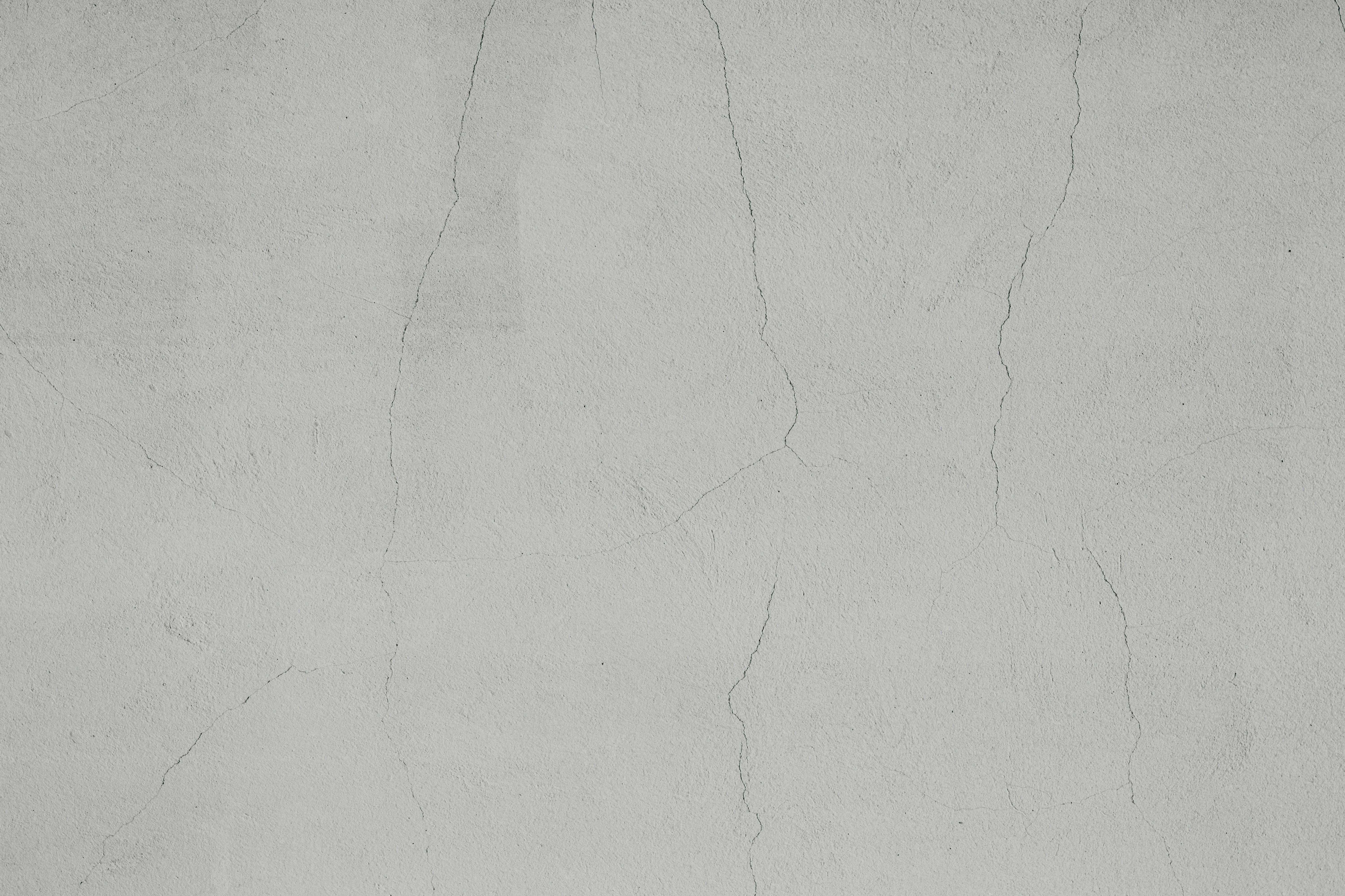 A light grey concrete wall with thin vertical cracks across the surface