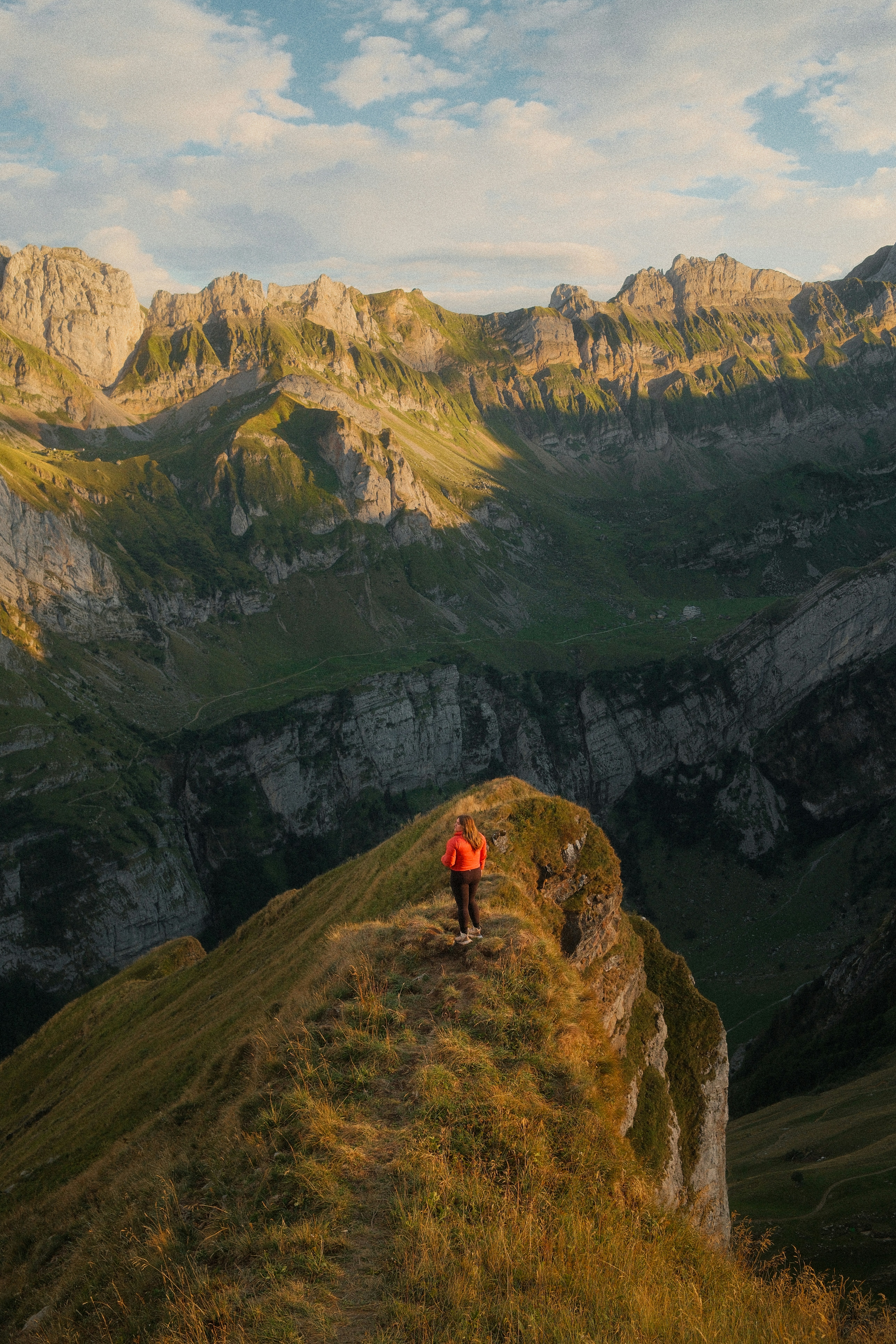 A woman in an orange jacket on a rocky ridge in Schwende-Rüte, Switzerland