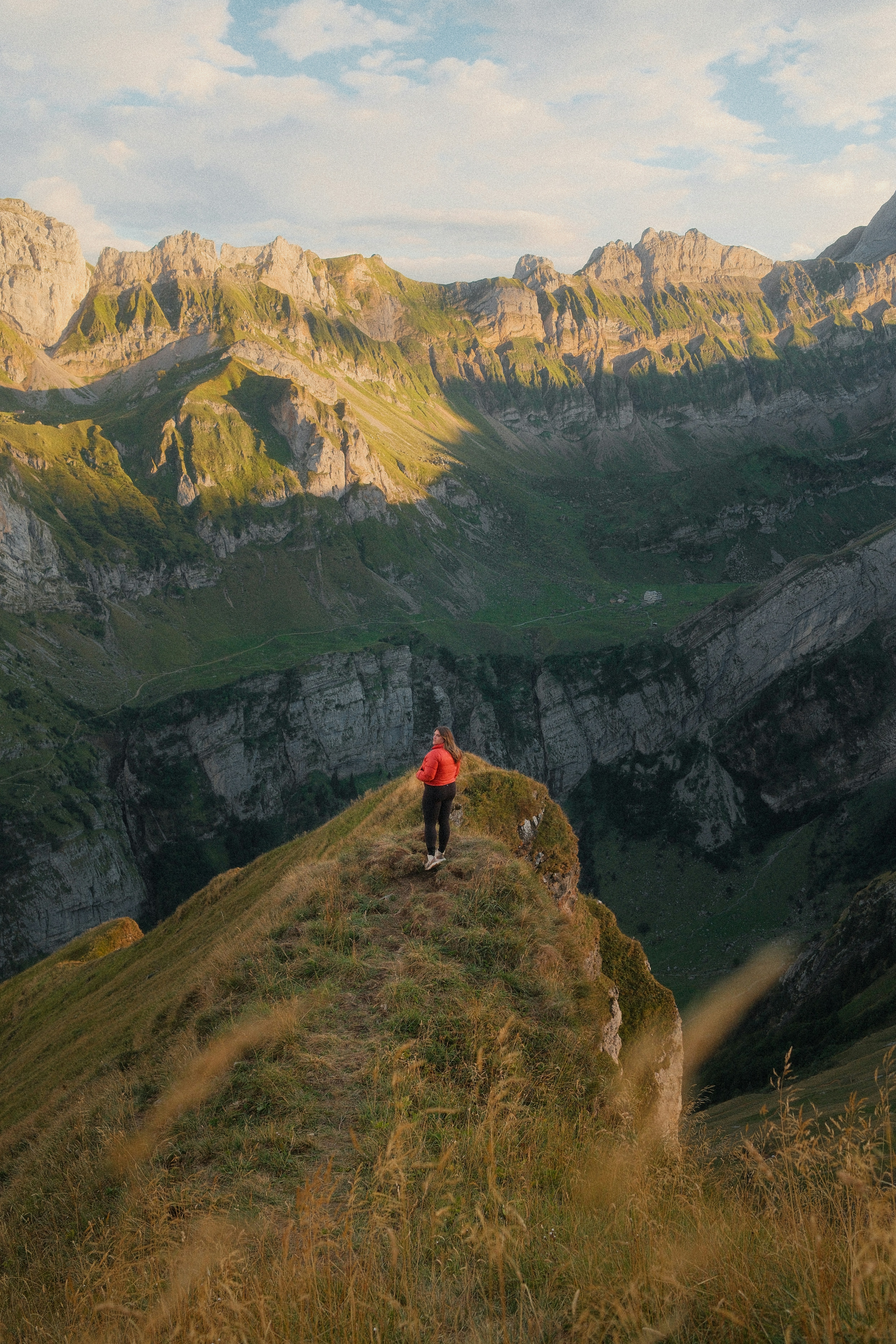 Une personne en veste rouge sur une crête herbeuse à Schwende-Rüte, en Suisse