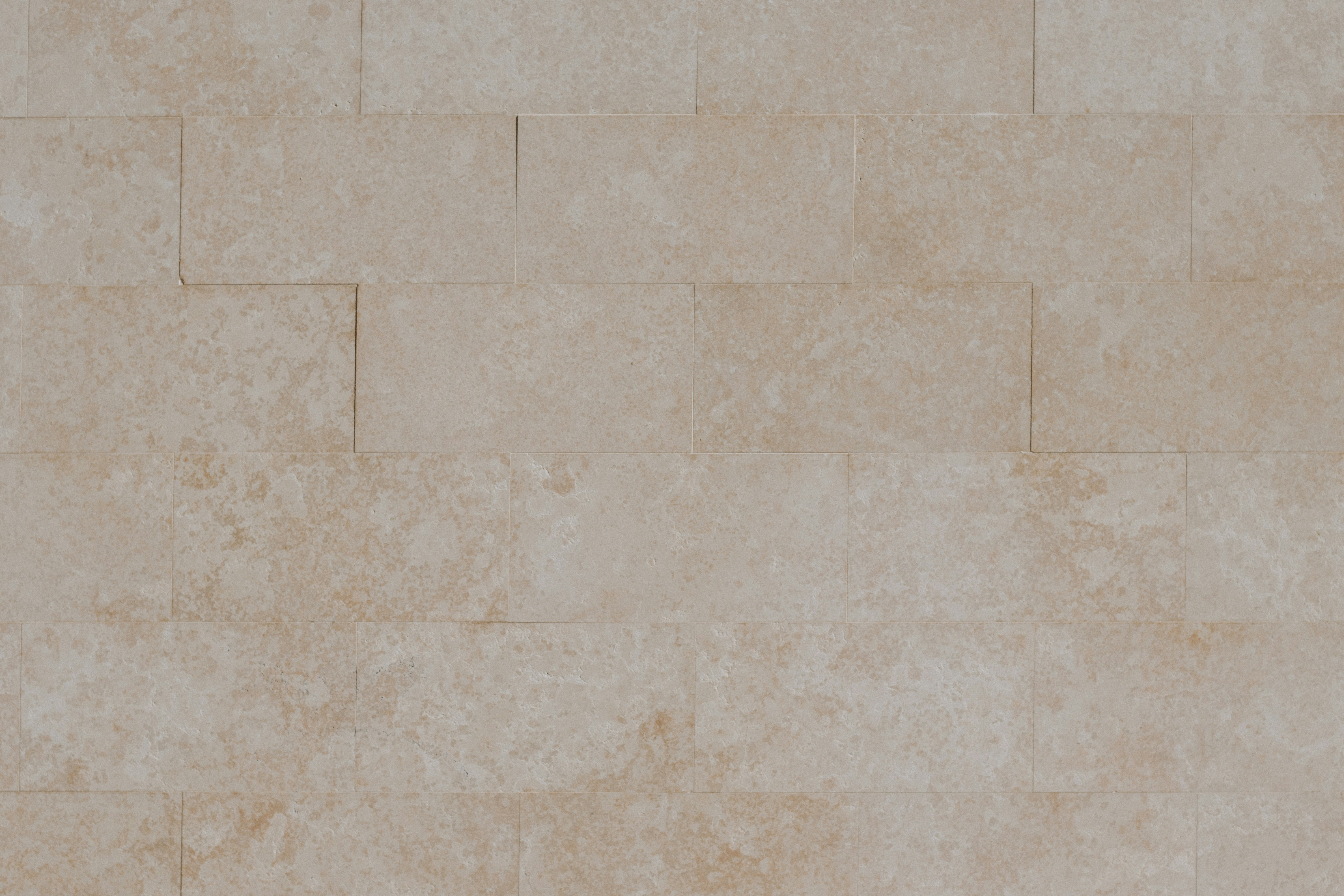 A wall of rectangular beige travertine tiles with a natural porous texture