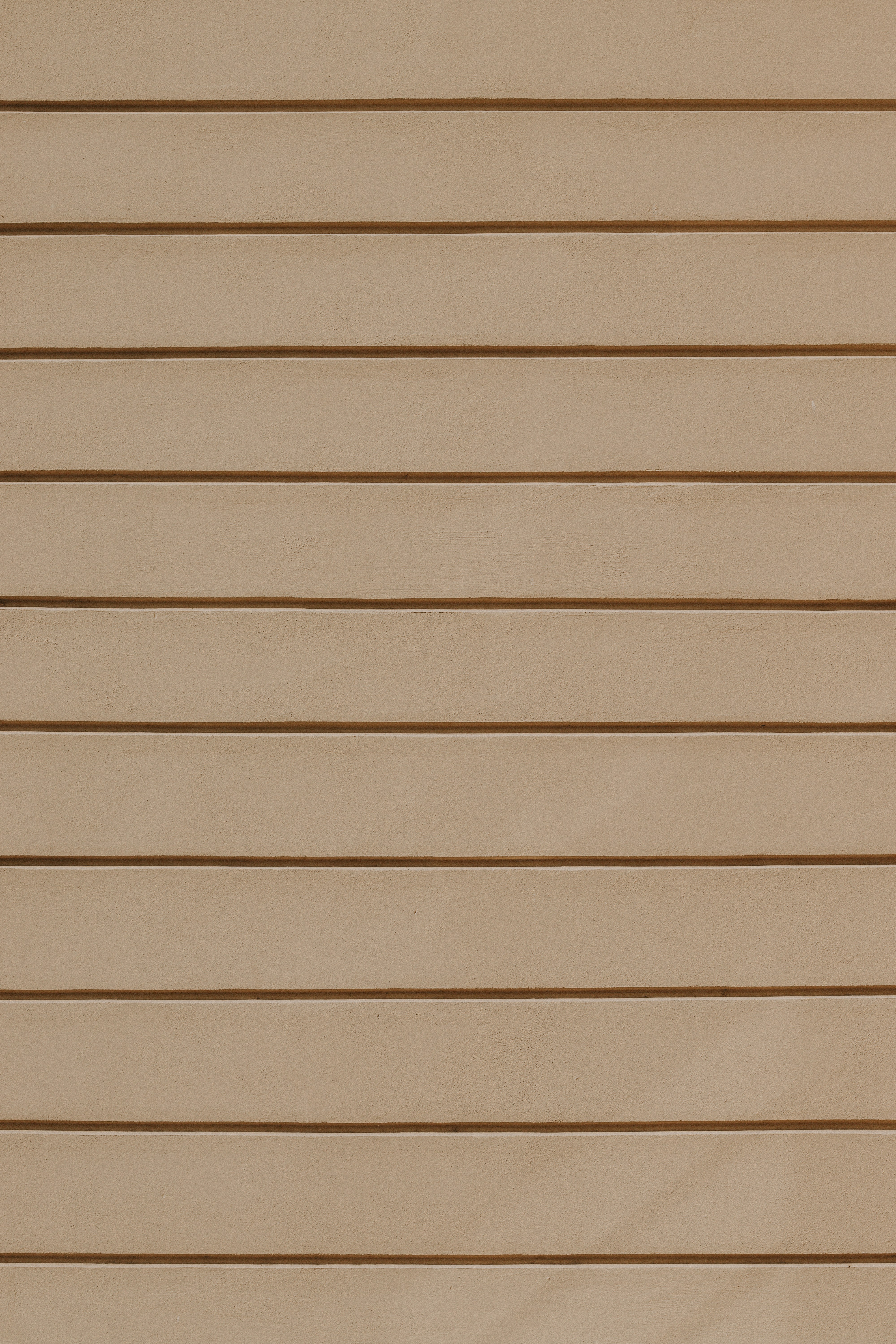 A beige wall with horizontal recessed lines creating a repeating pattern