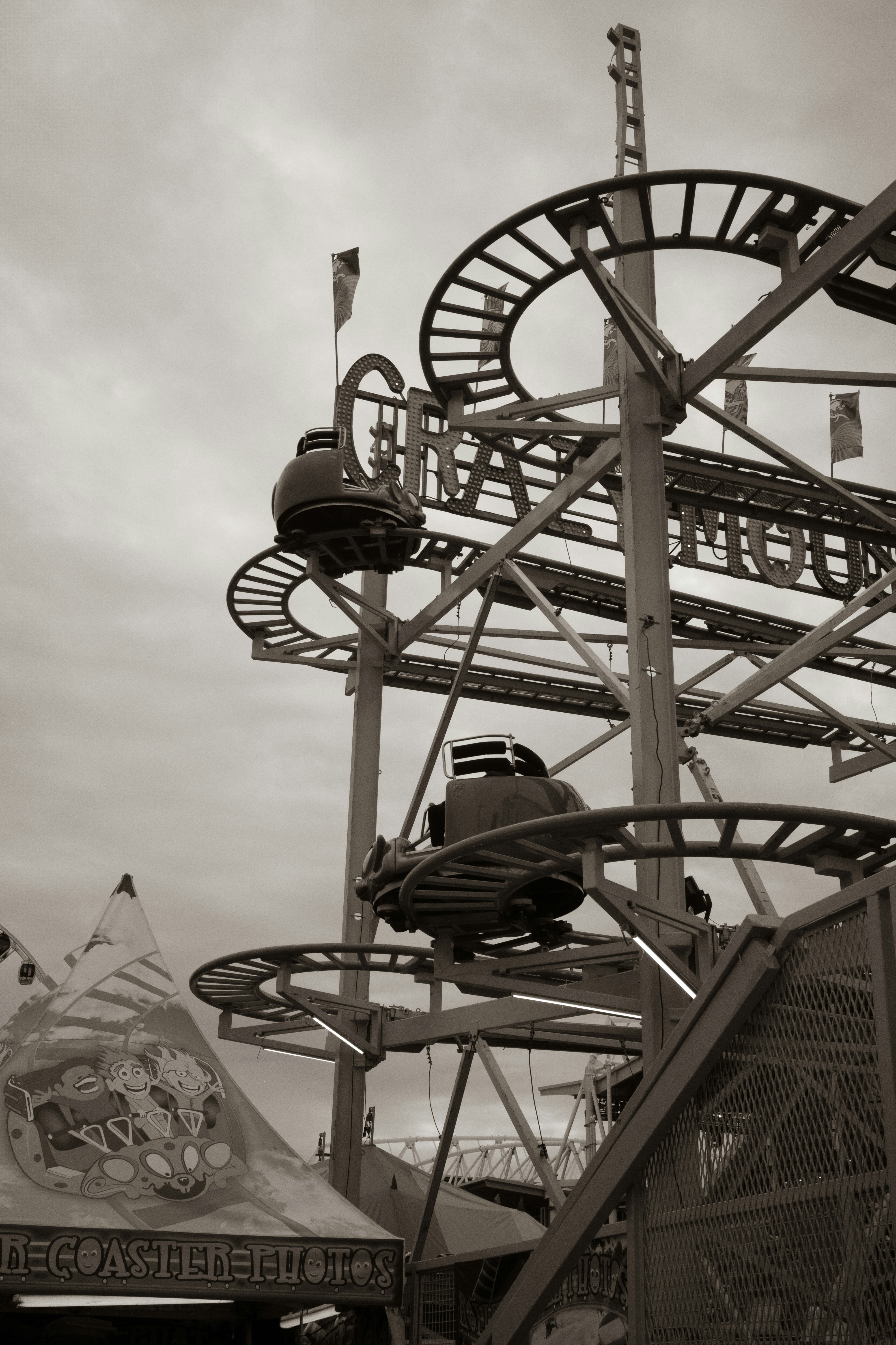 A roller coaster track with circular cars at a fairground under a cloudy sky