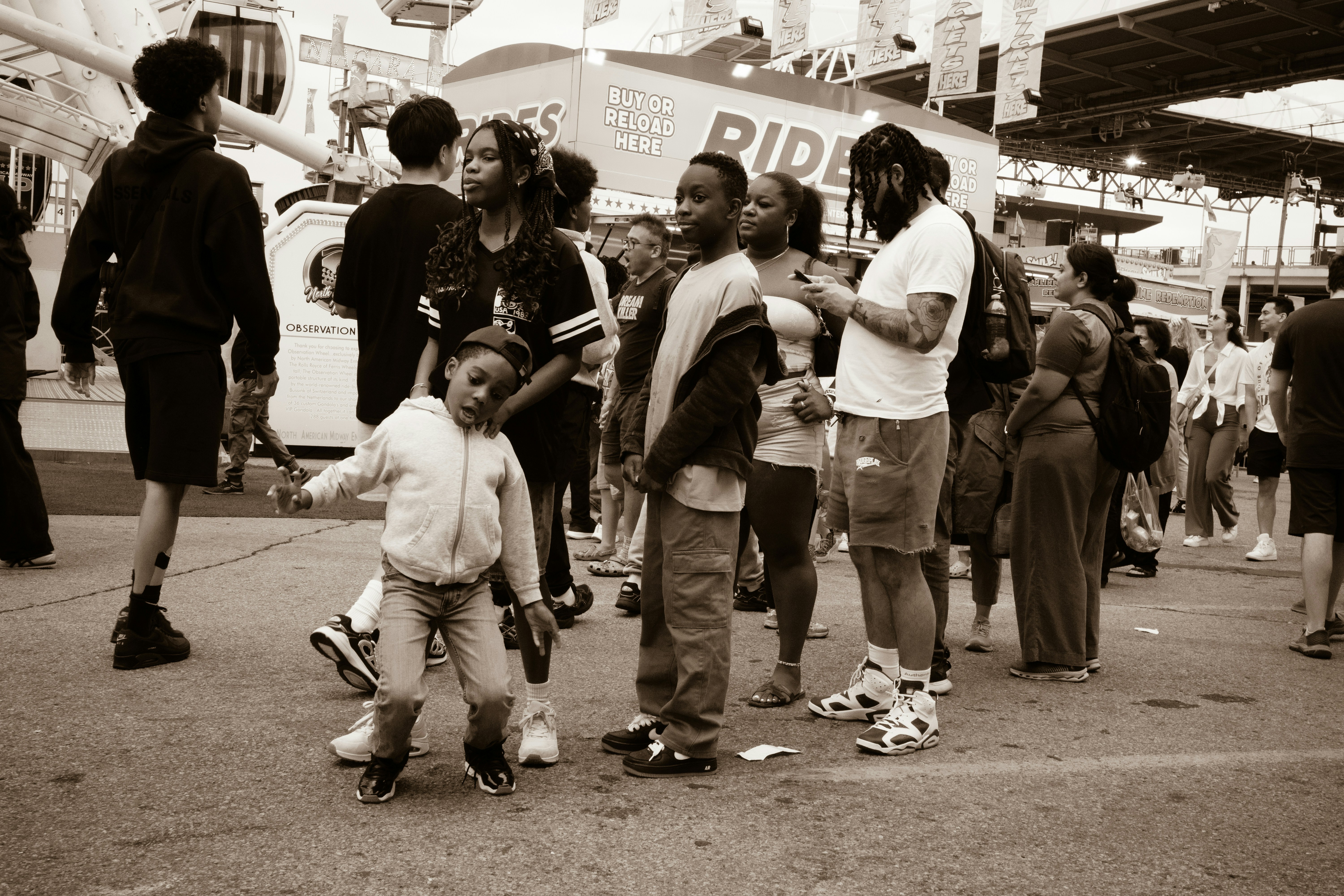 A group of people waiting in line at a fairground near a ride