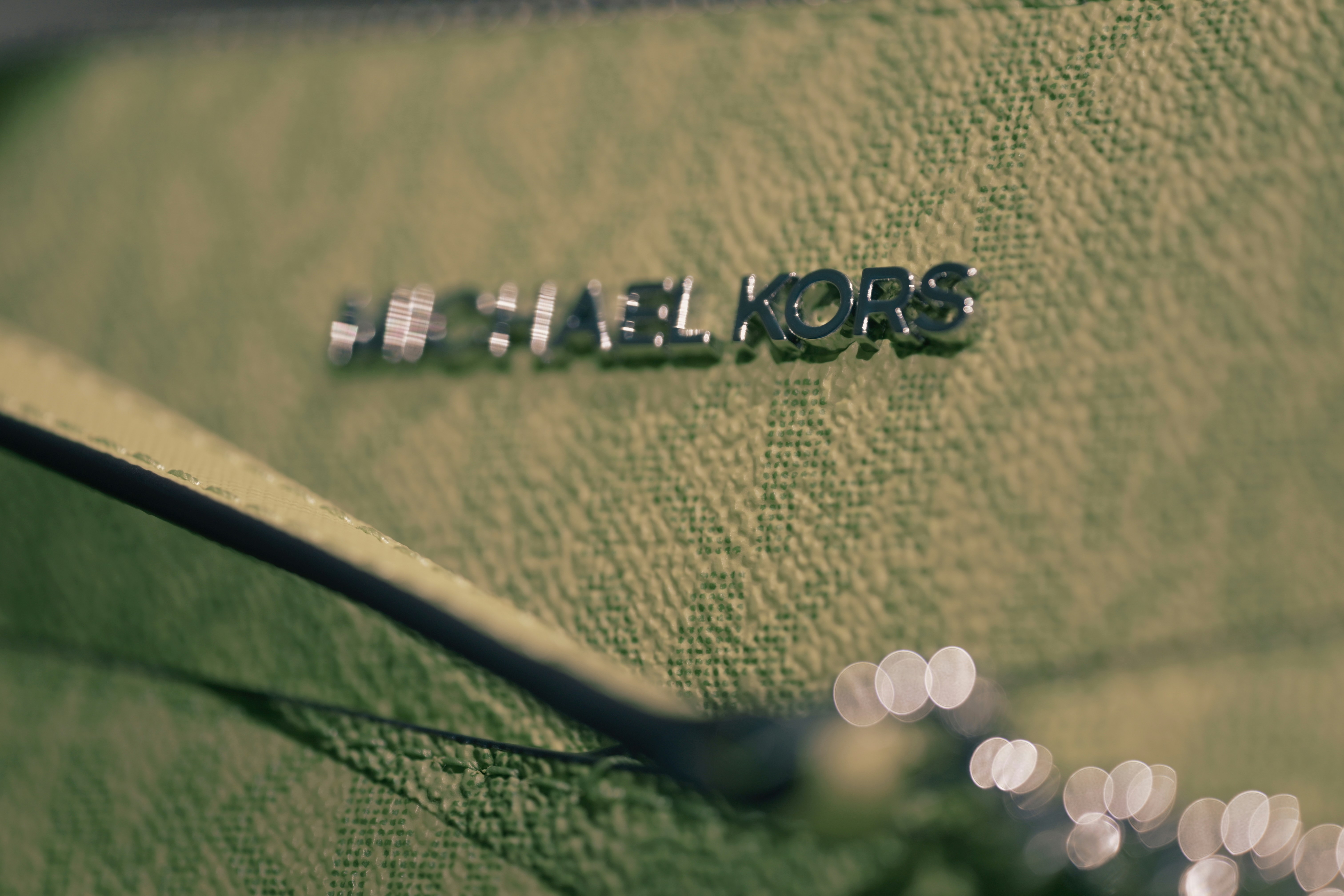 A textured light green surface with a metallic logo and soft bokeh highlights