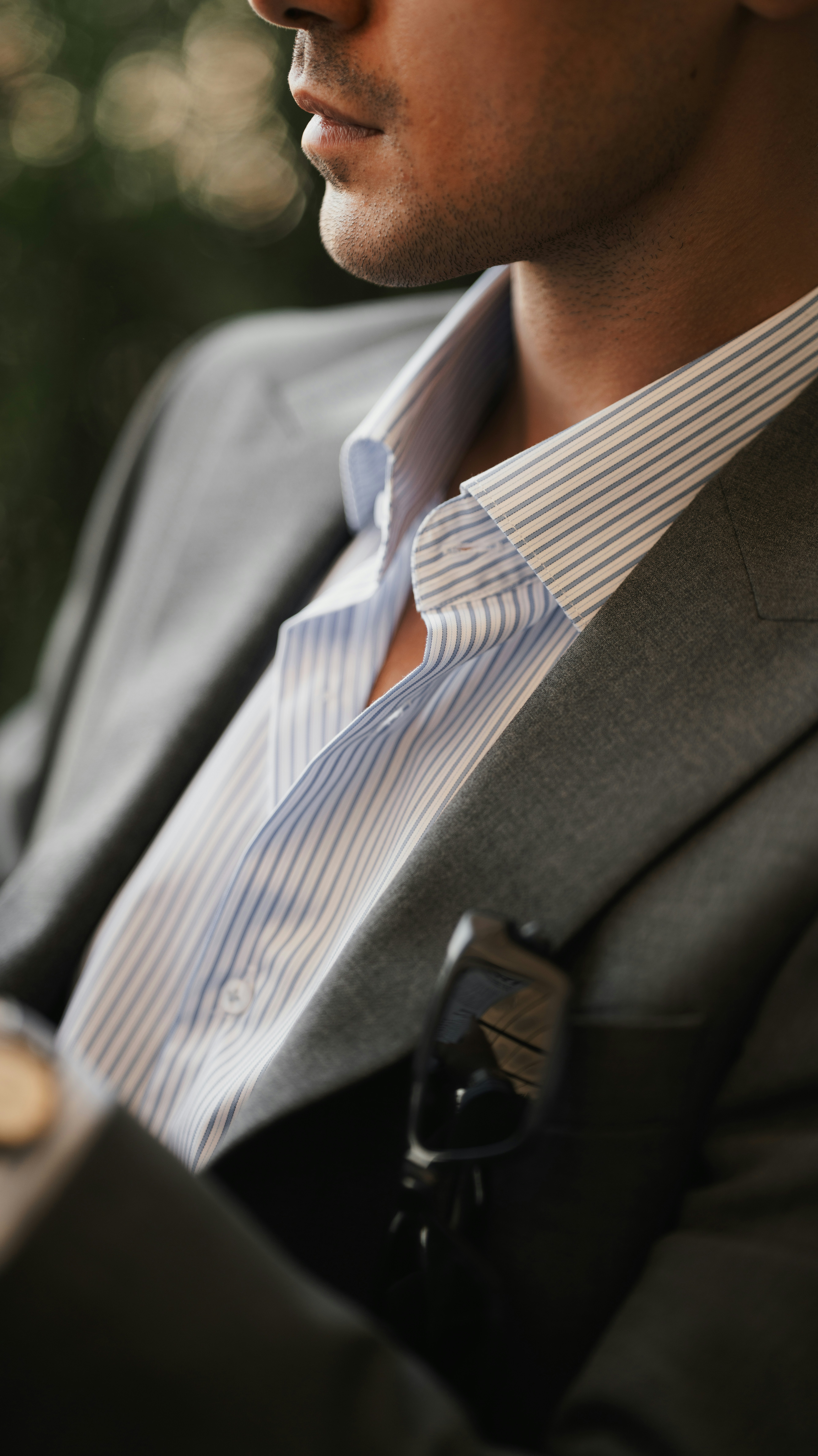Ein Mann in einem grauen Blazer und einem hellblau gestreiften Hemd mit Sonnenbrille