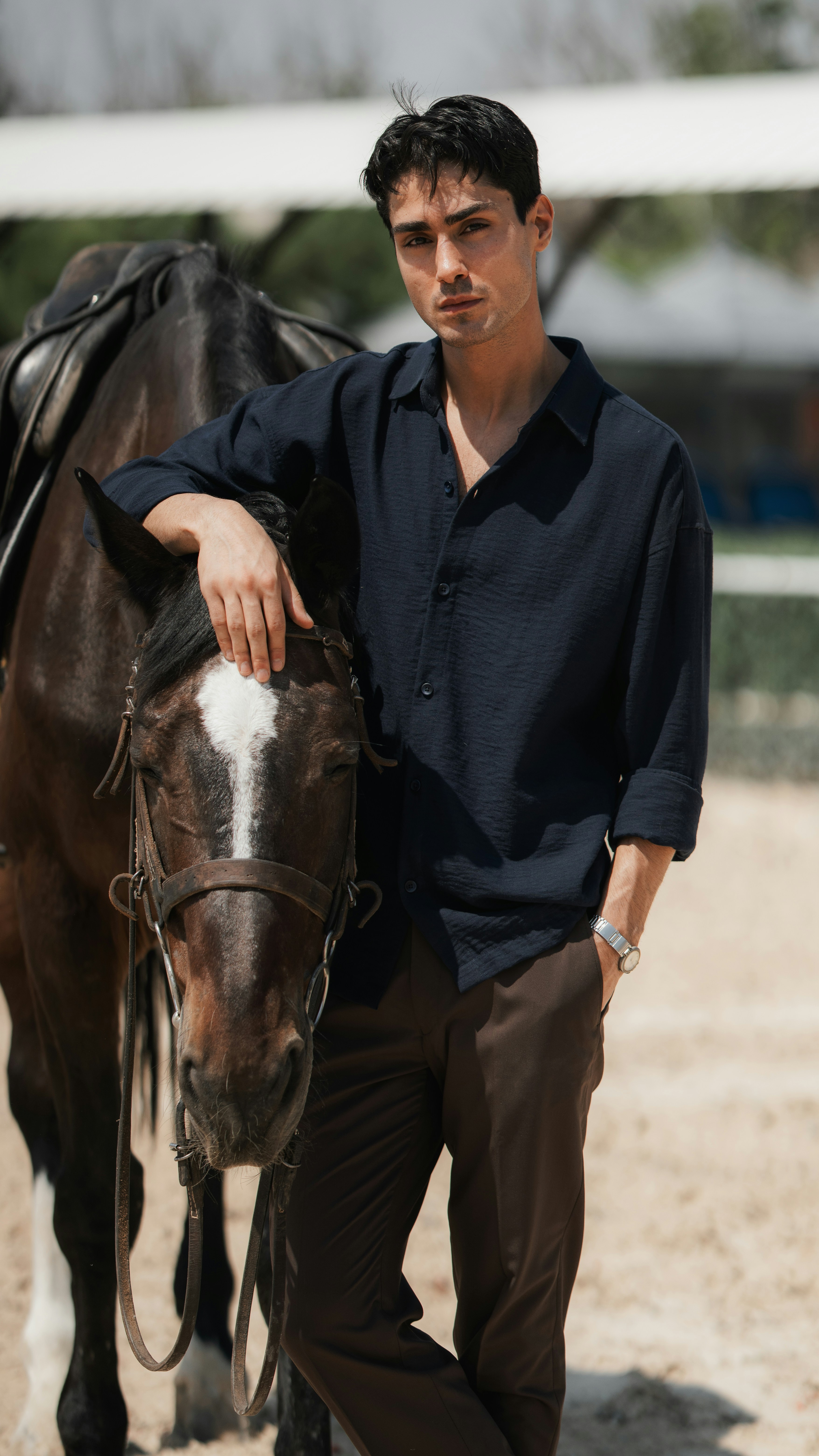 A man in a dark shirt resting his hand on a brown horse