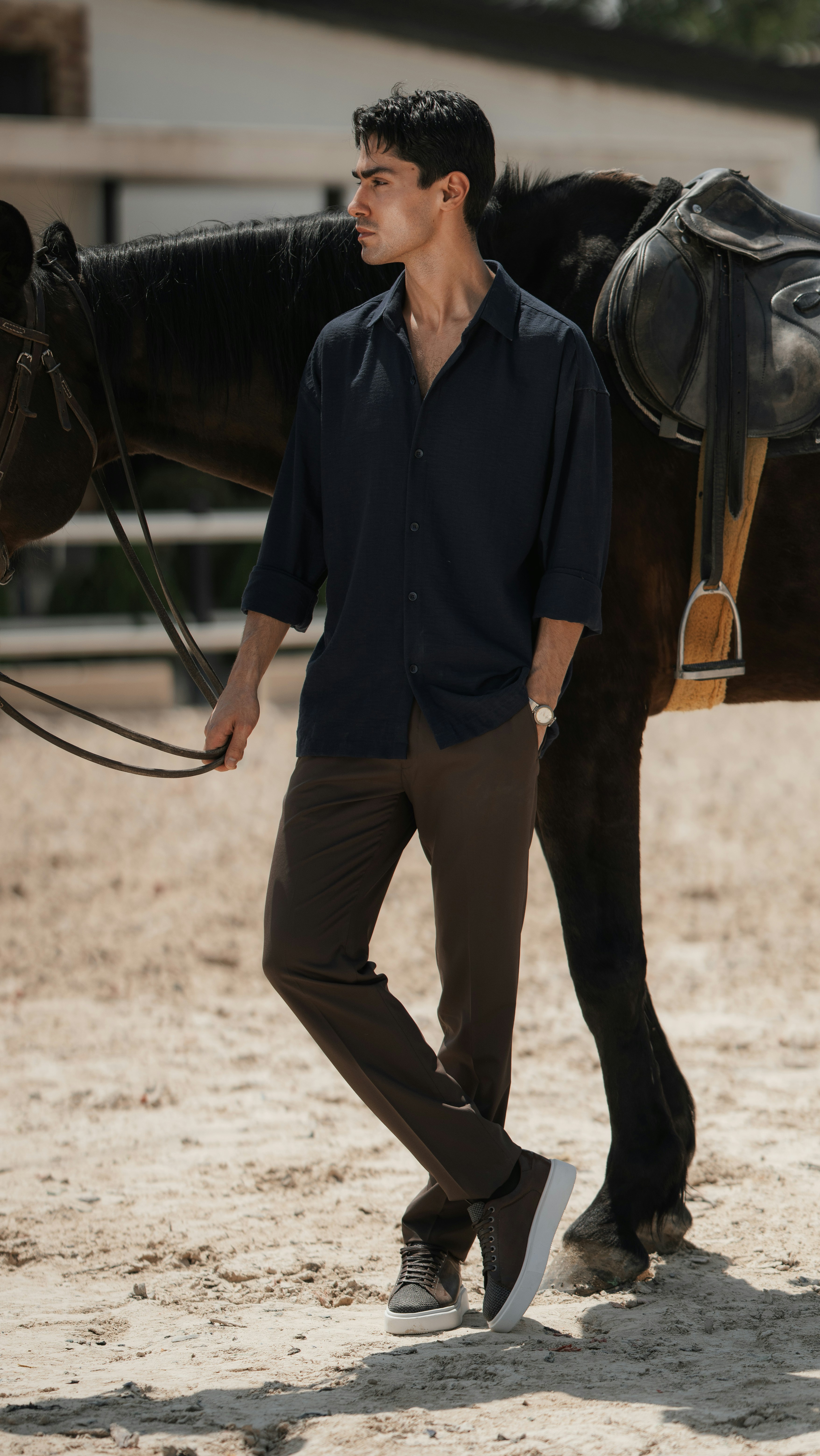 Leading a saddled horse, black shirt and trousers