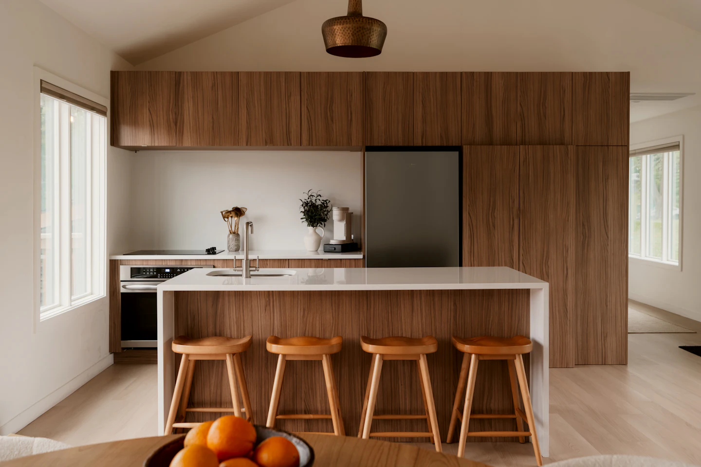 Walnut cabinetry and a white island with wood stools