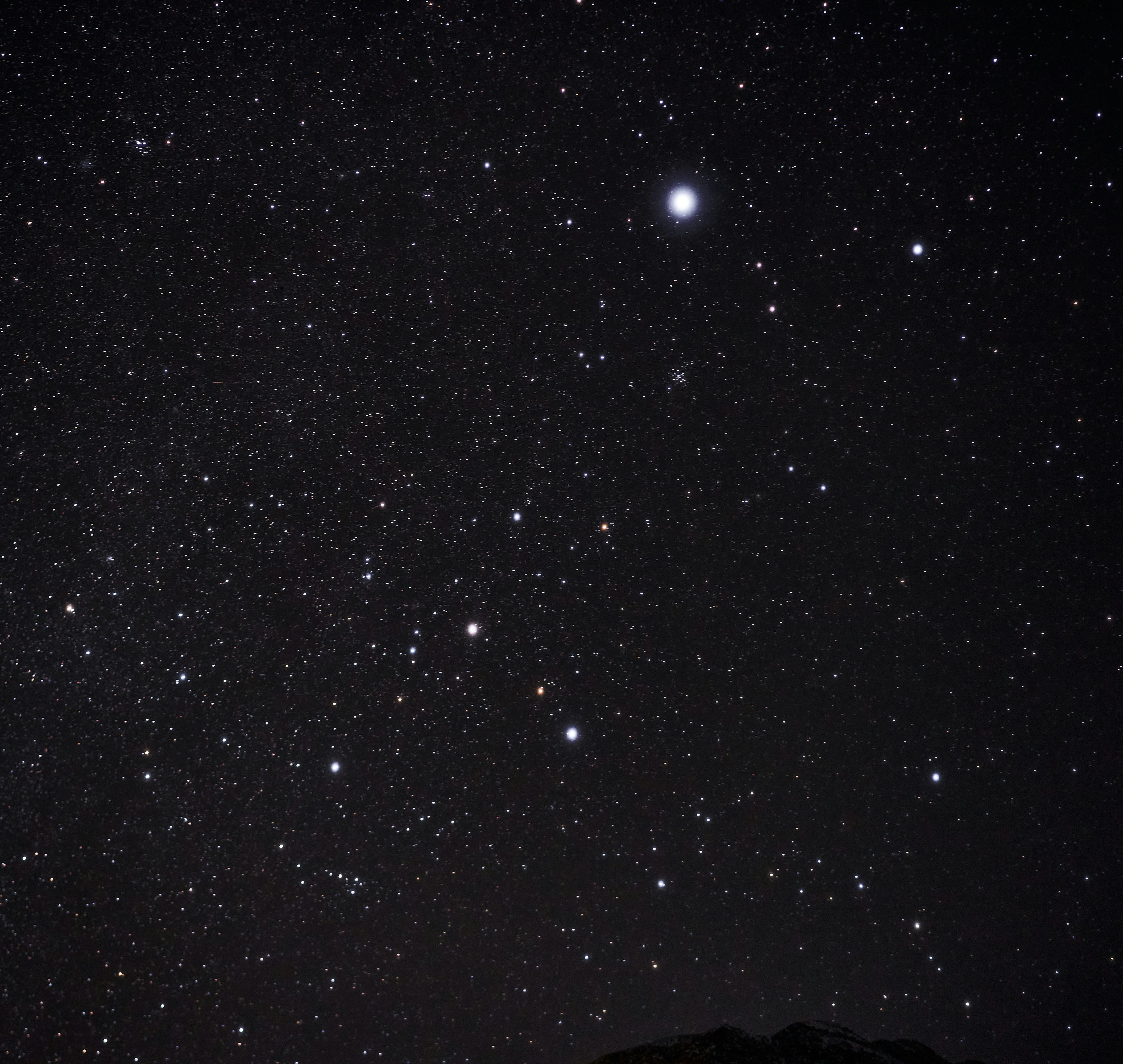 A vast night sky filled with countless bright stars above a dark mountain silhouette