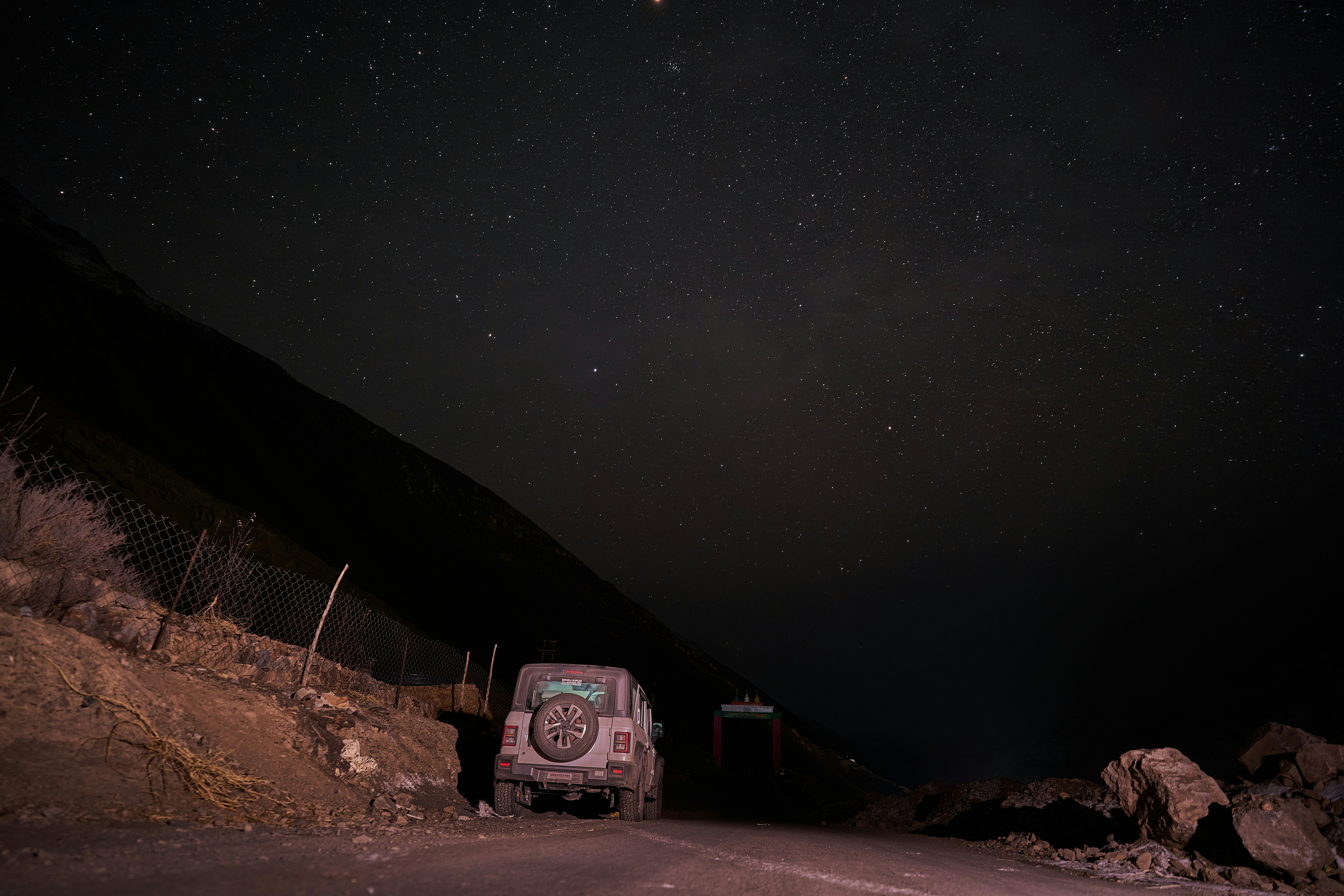 An off-road vehicle parked on a dark road beneath a vast starry sky