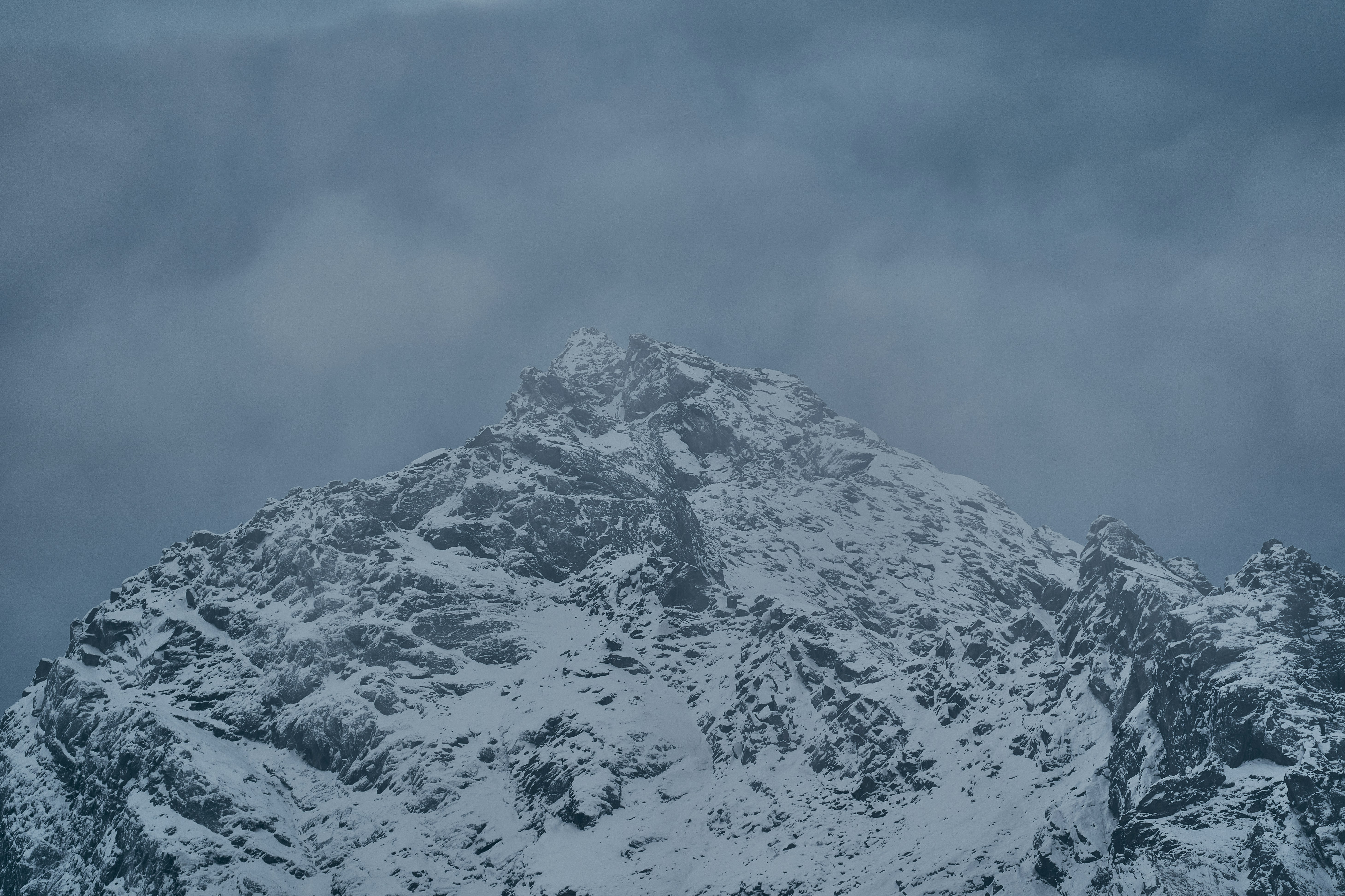 A snow covered mountain peak under a dark and cloudy sky