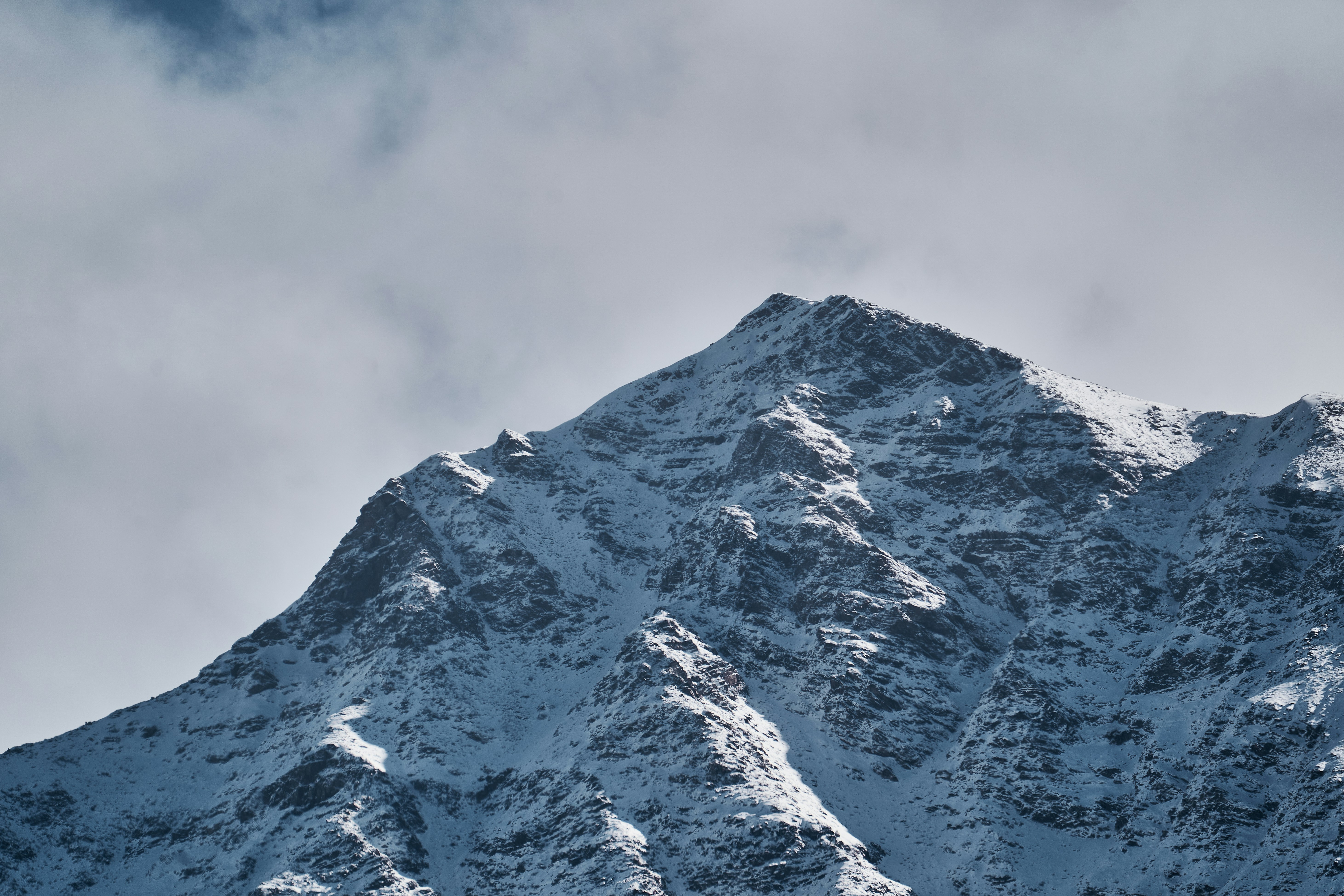 A snow covered mountain peak against a cloudy sky
