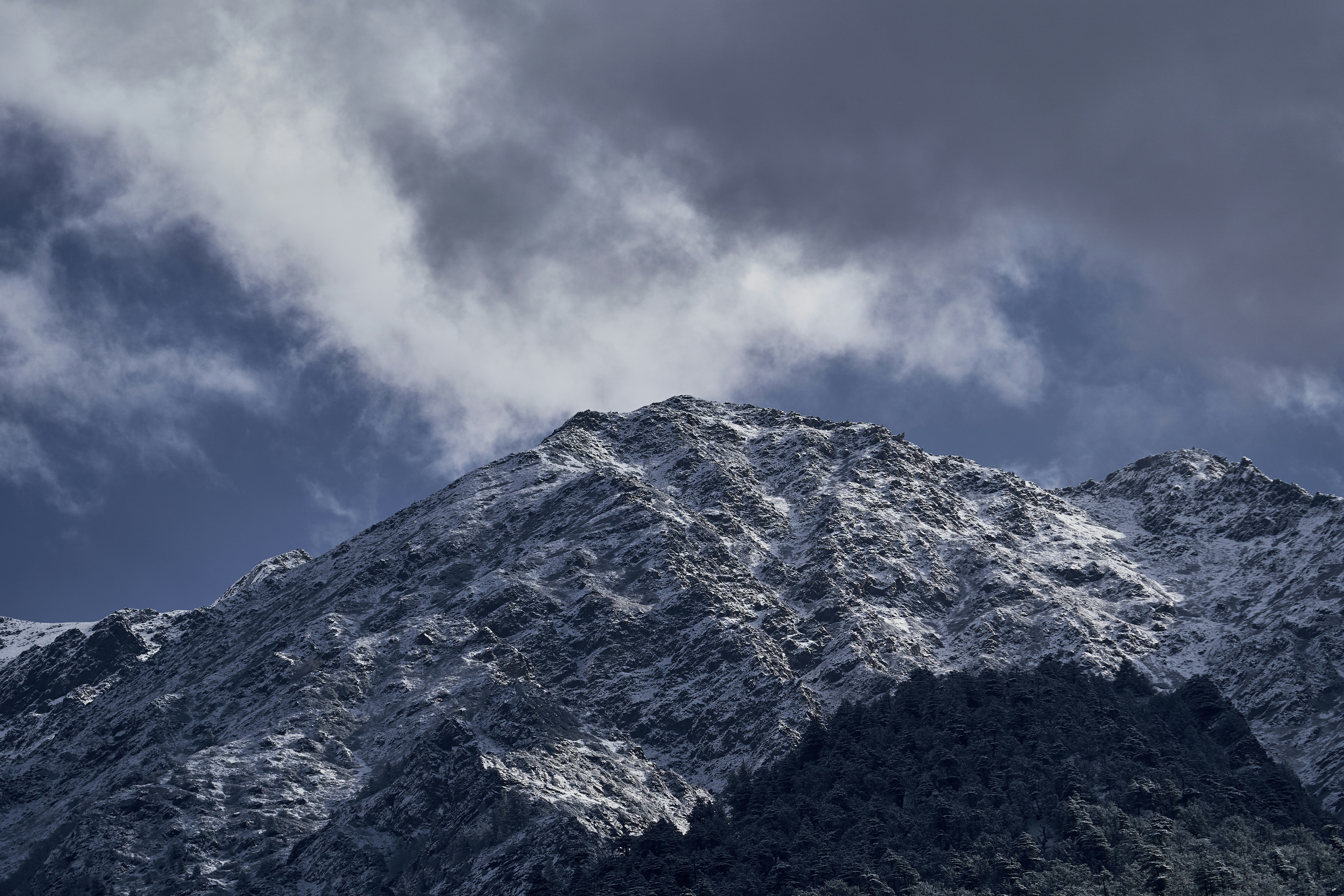A snow-covered mountain peak under a sky with dark, heavy clouds