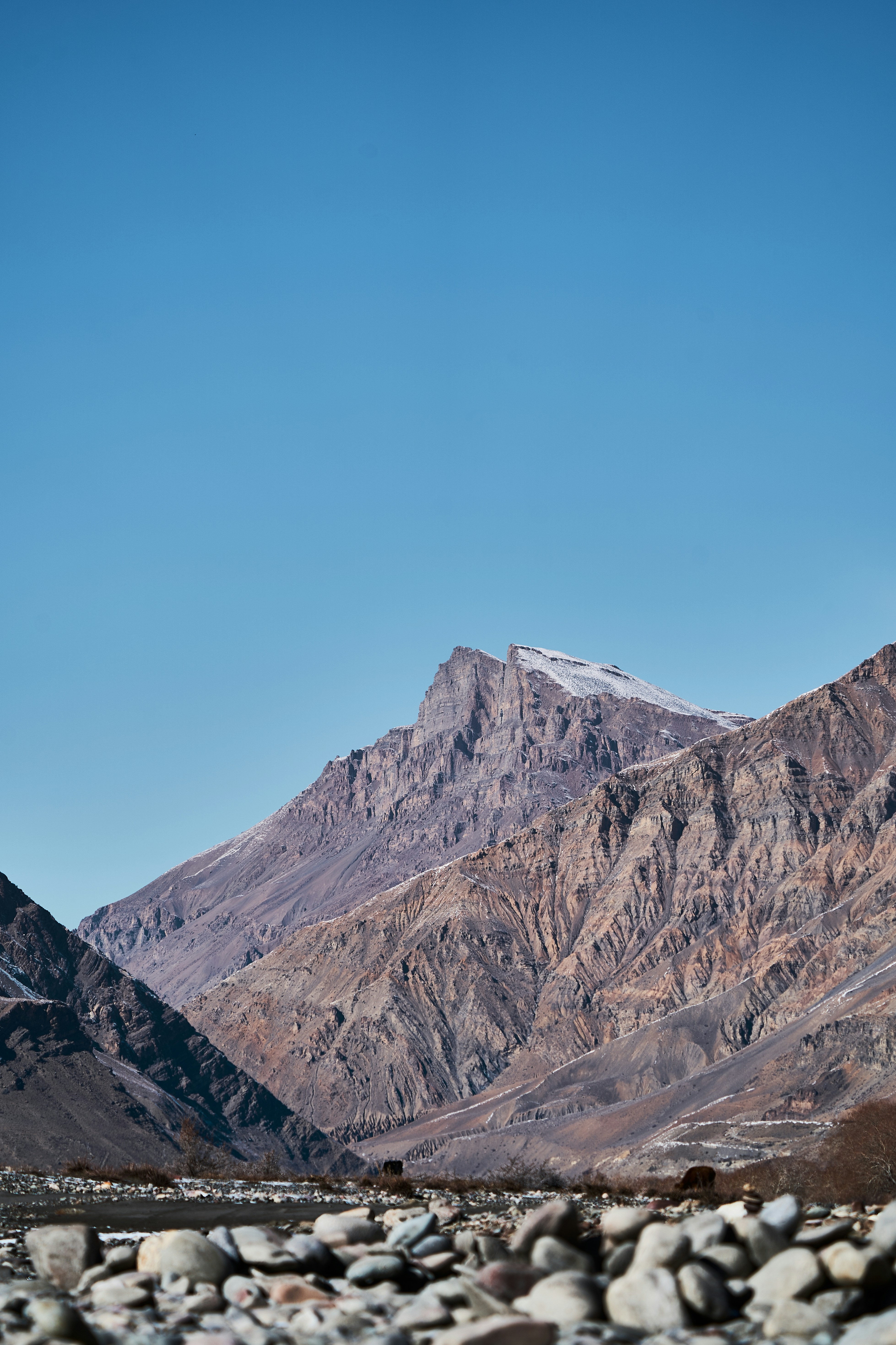 Rugged brown mountains with light snow under a clear blue sky