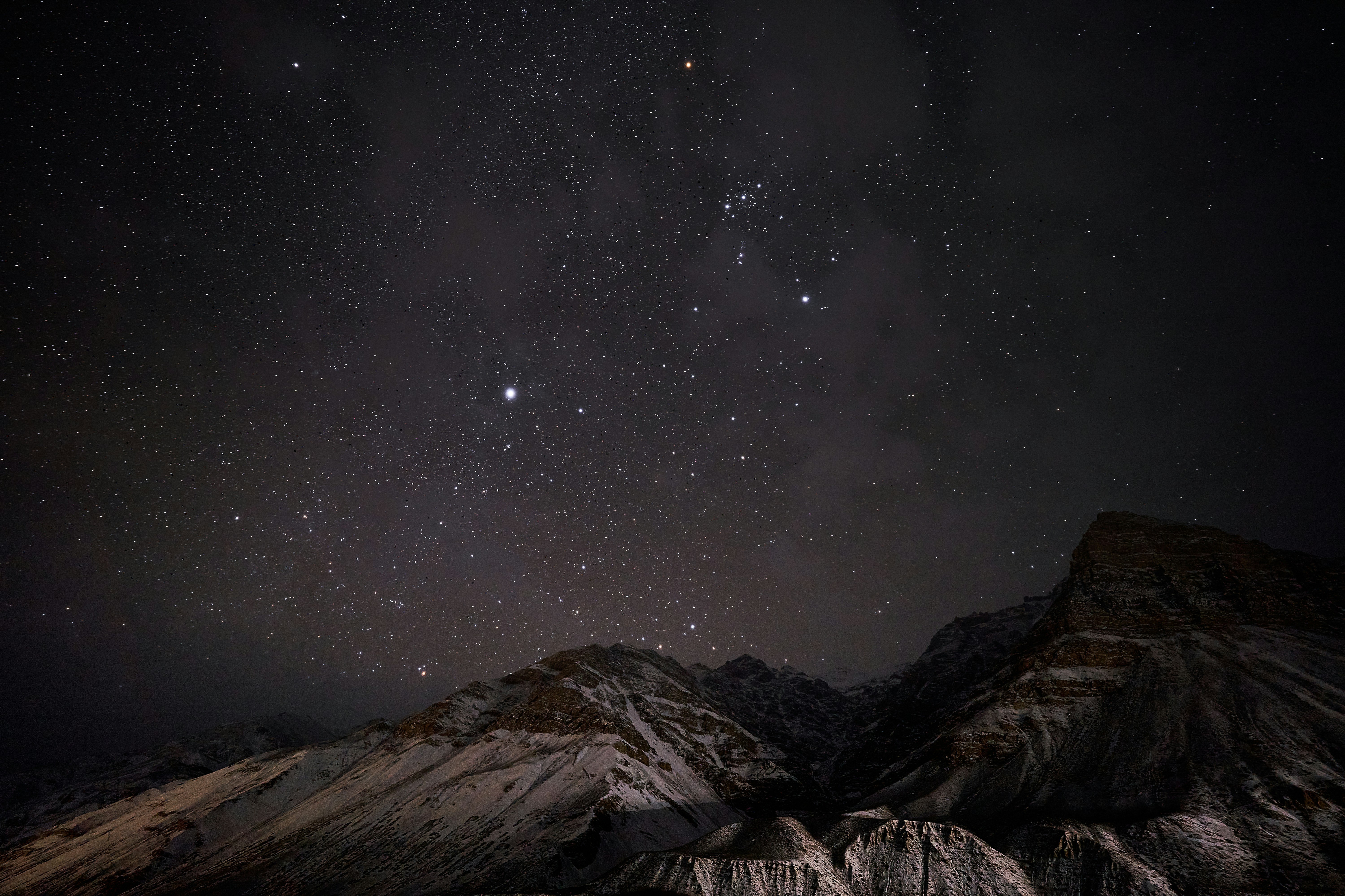 A starry night sky above snow-covered mountain peaks