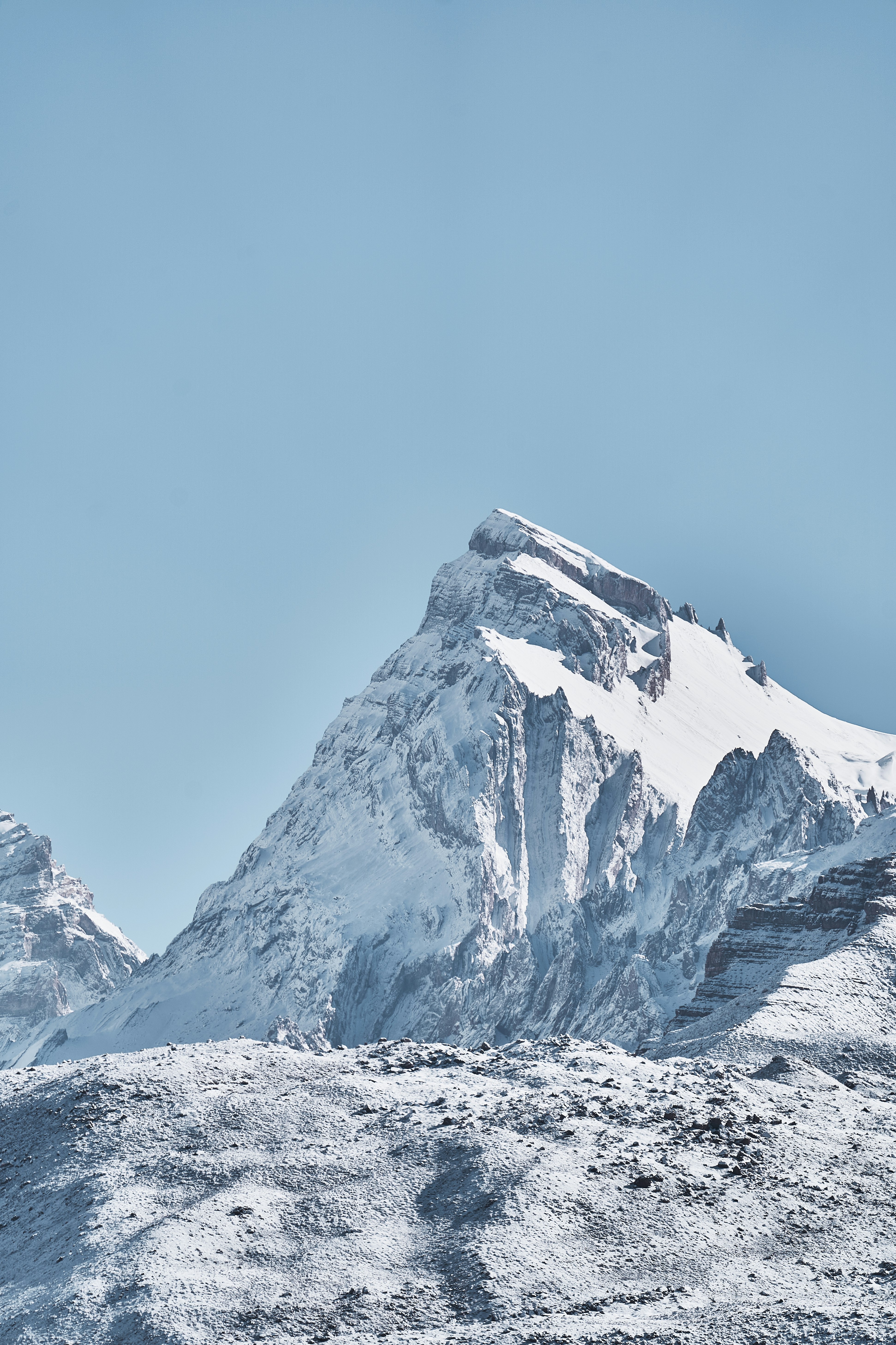 A snow-covered mountain peak rising against a clear light blue sky