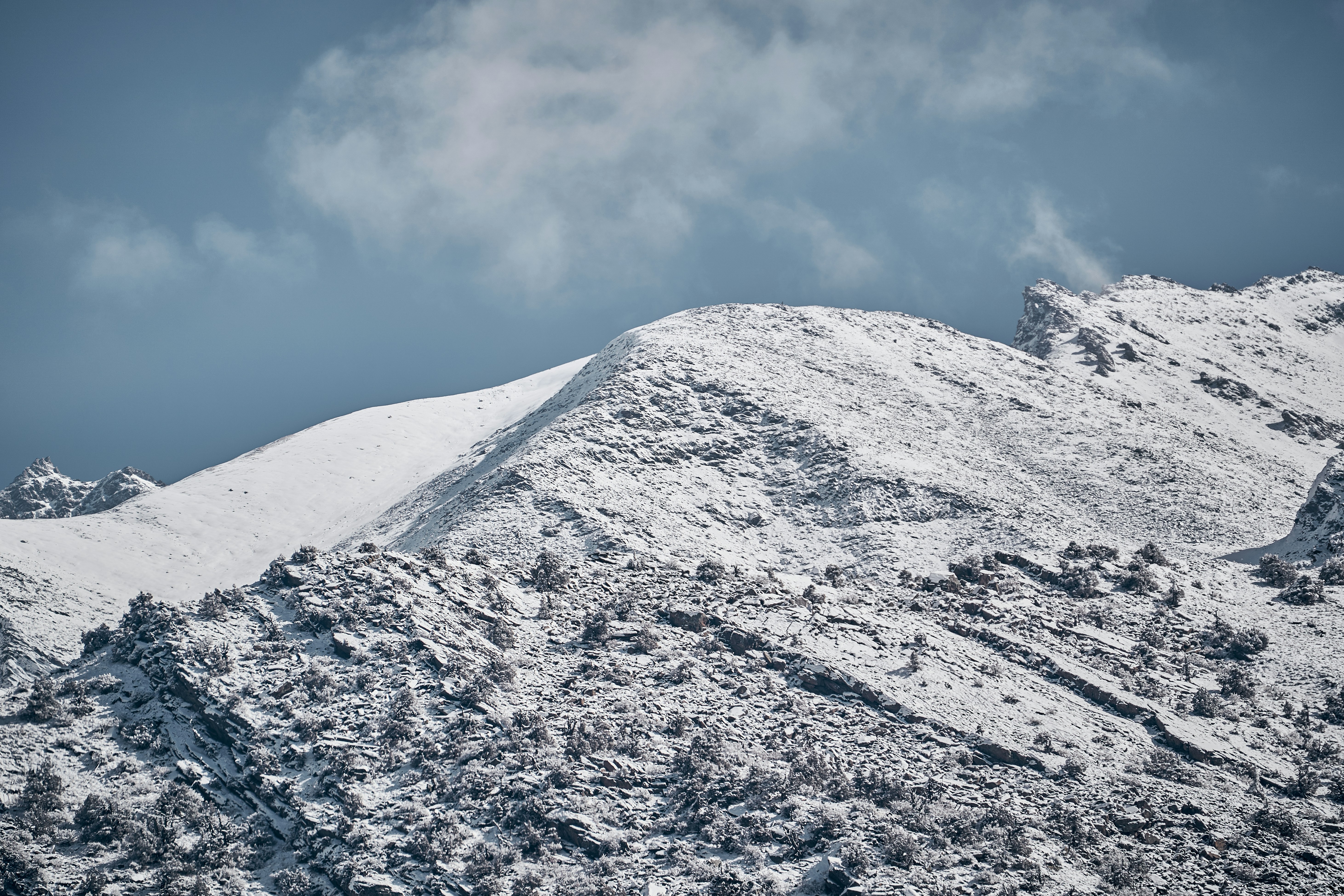 Snow-covered mountain peaks under a blue sky with scattered clouds