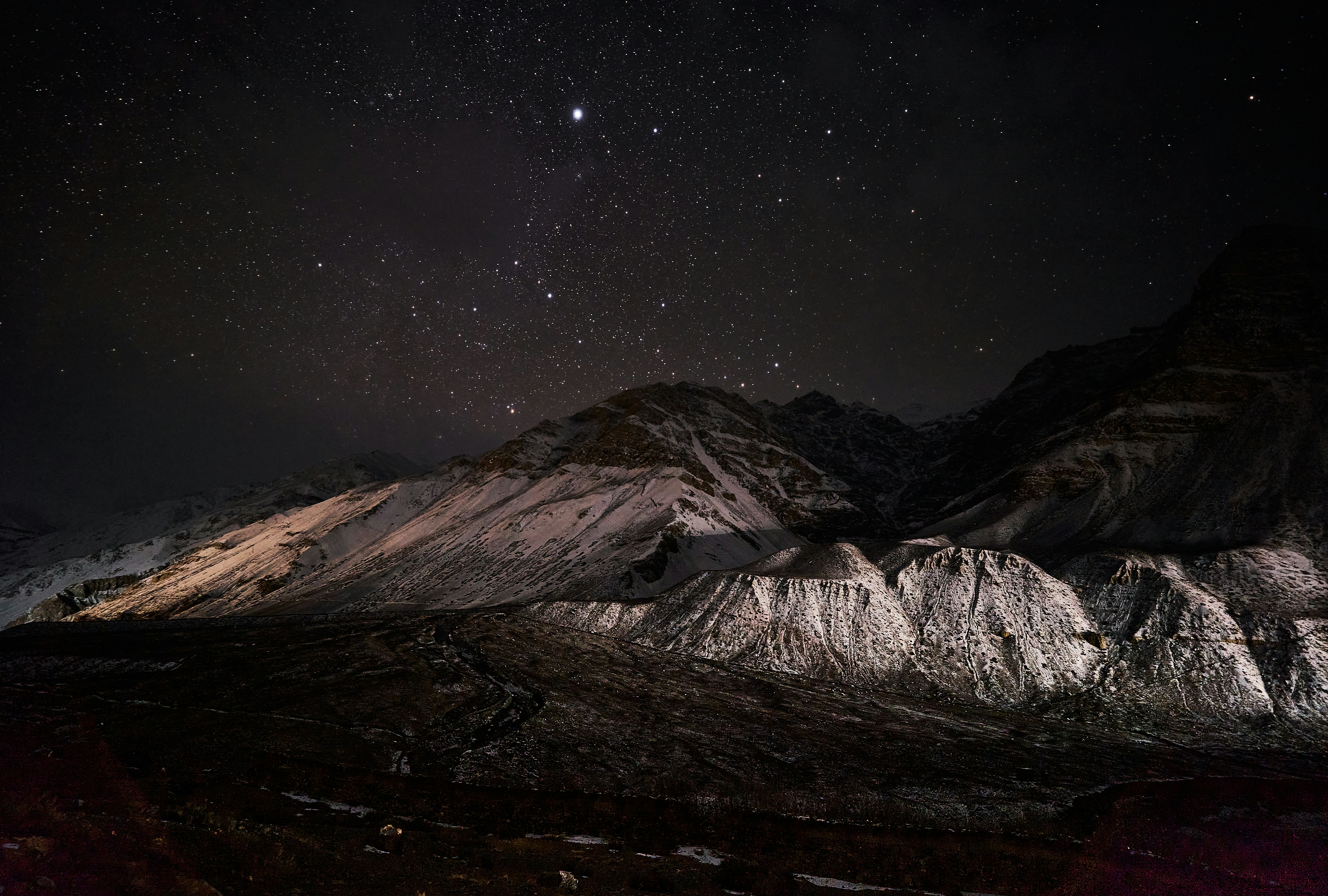 Snowy mountain peaks under a vast night sky filled with bright stars