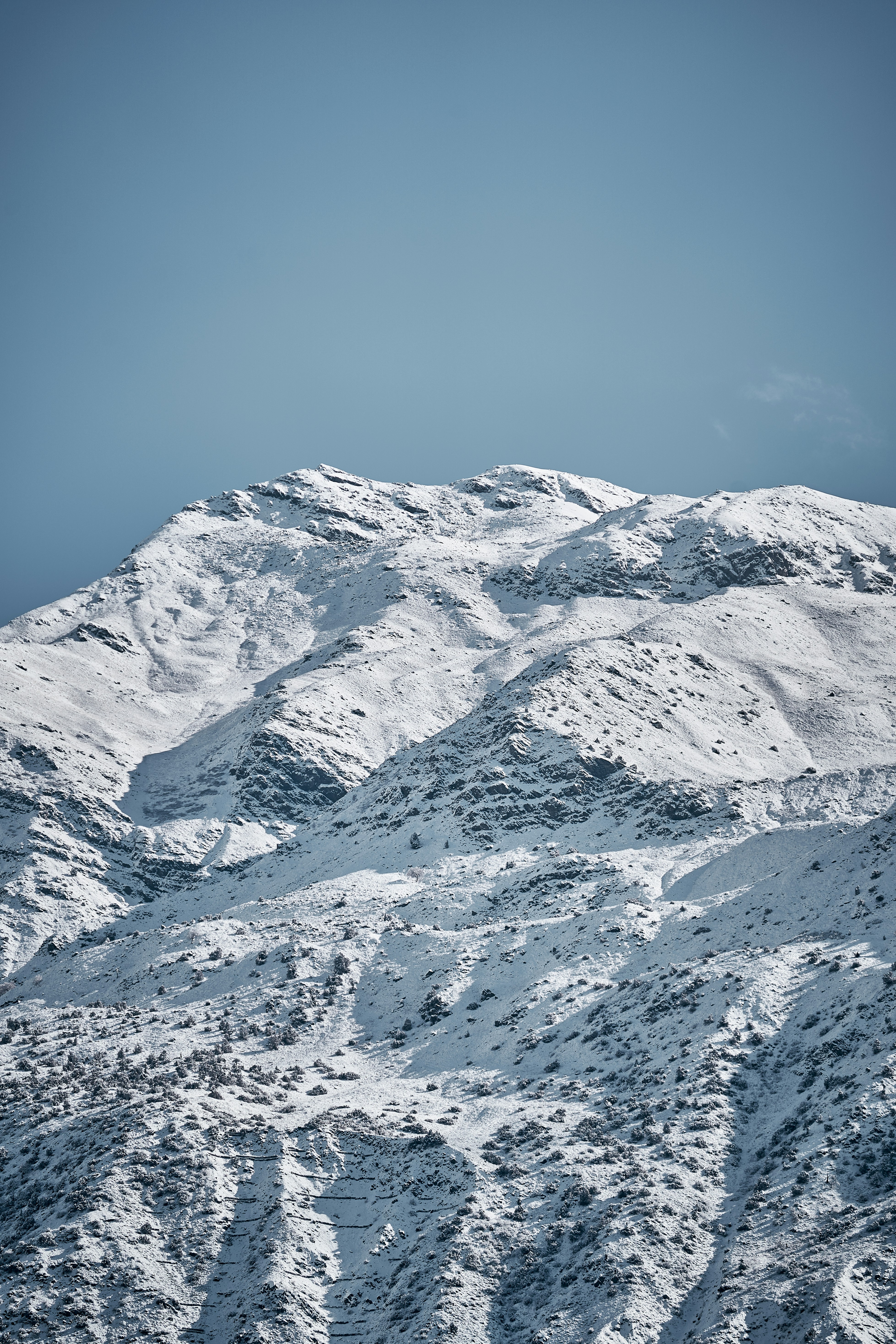 Snow covered mountain peaks under a clear blue sky