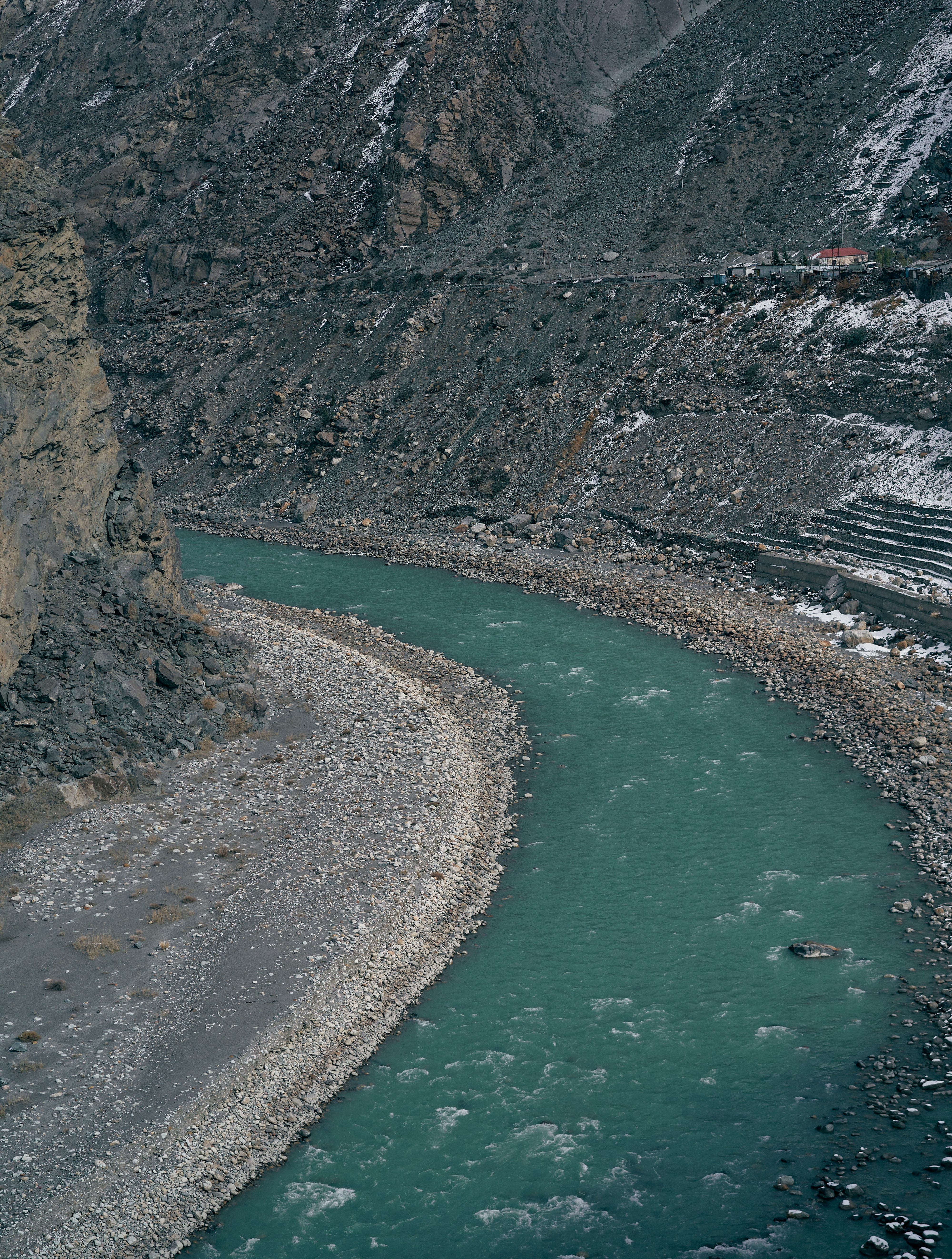 A turquoise river flowing through a deep rocky canyon with snow on the slopes