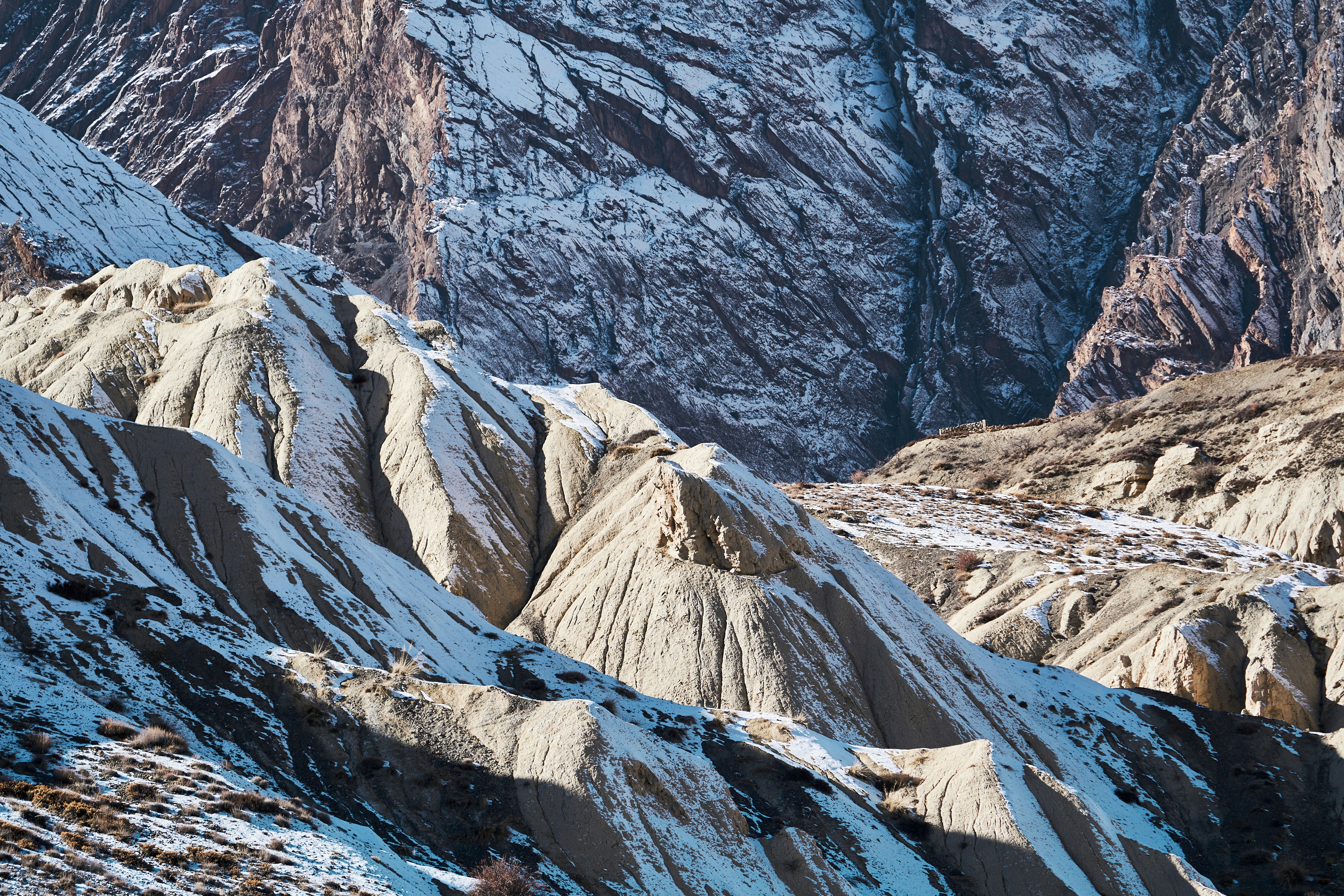 Snow-dusted rocky slopes and deep ridges in a rugged mountain landscape