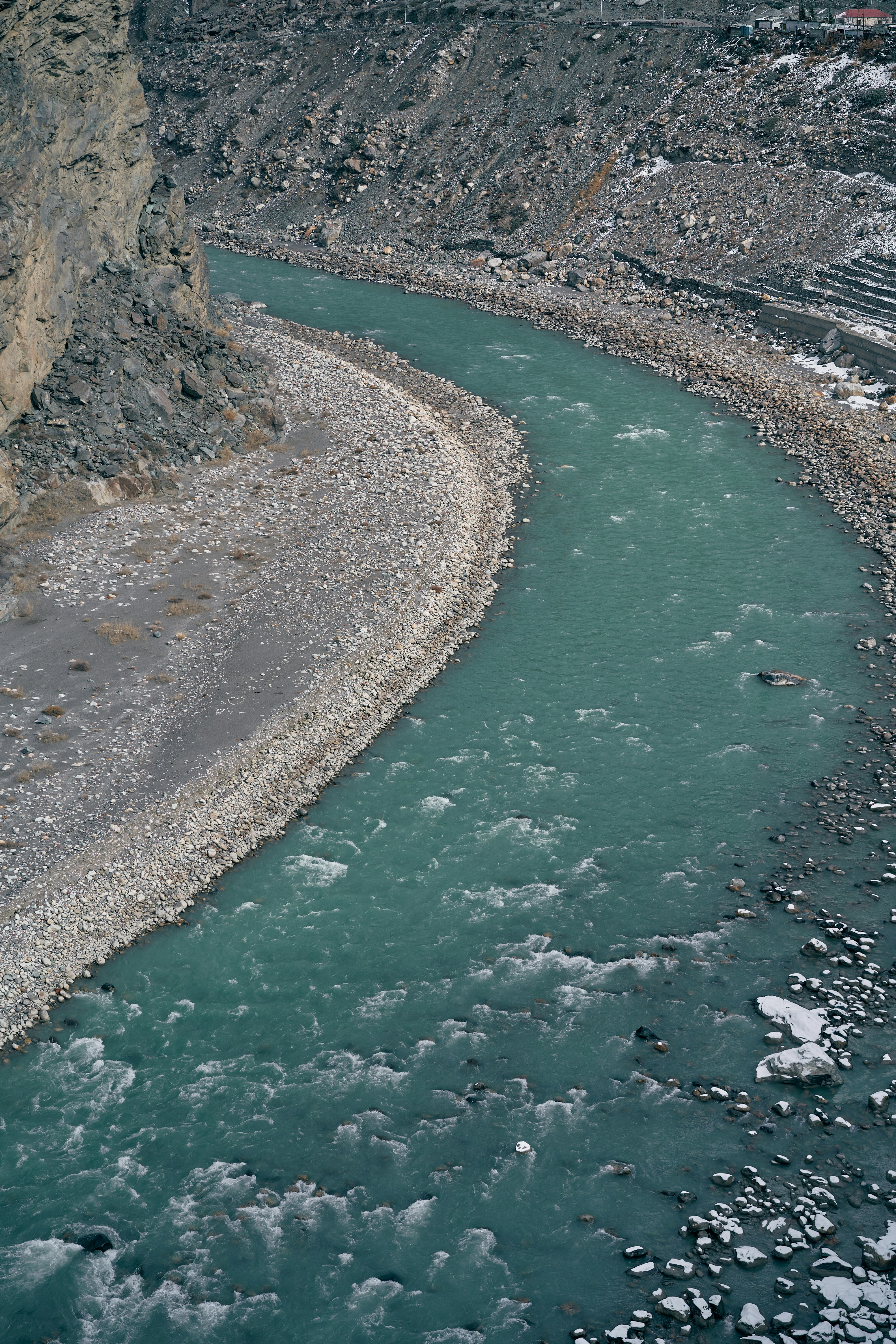 A turquoise river flowing through a rocky canyon with patches of snow