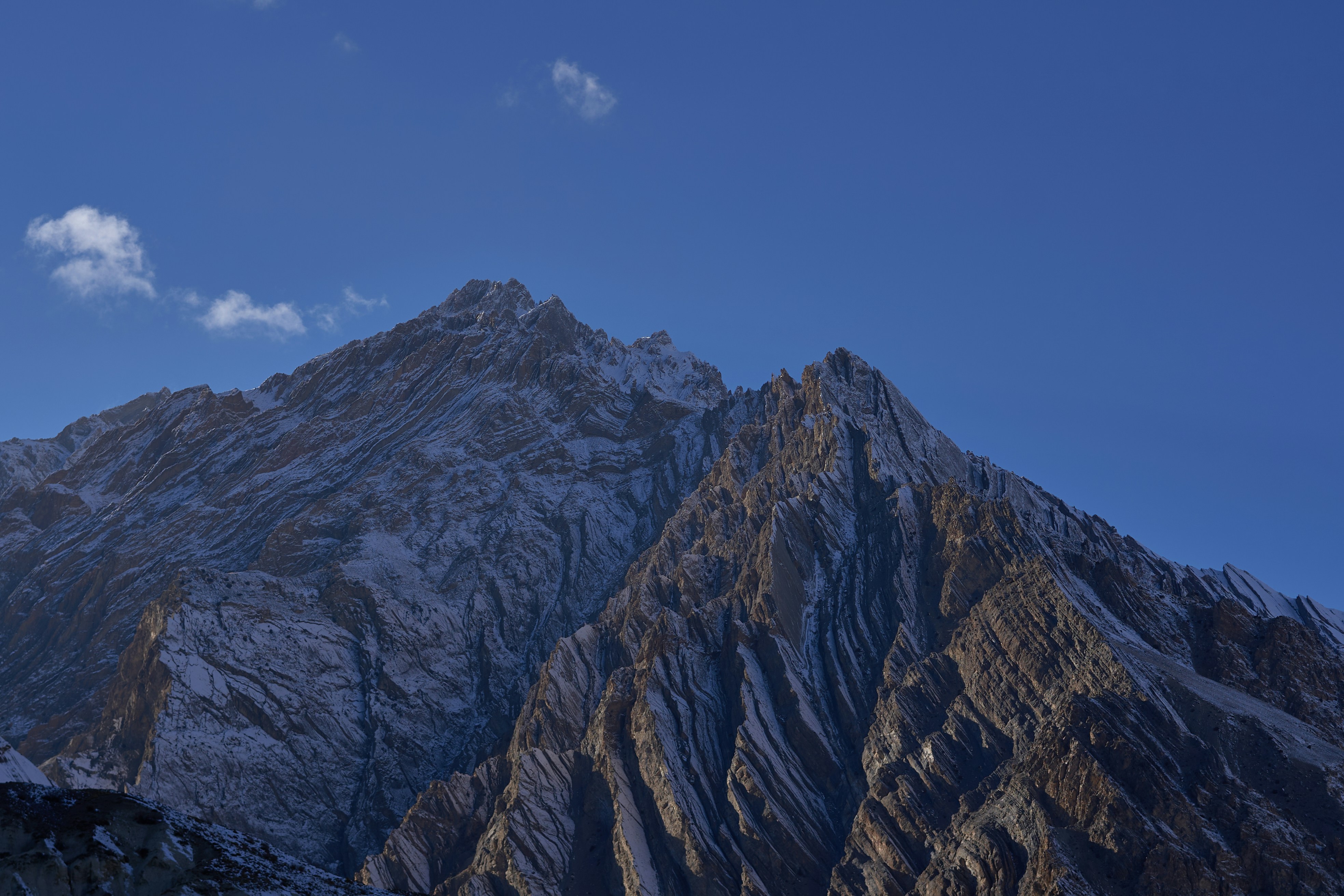 Snow-dusted jagged mountain peaks against a clear deep blue sky