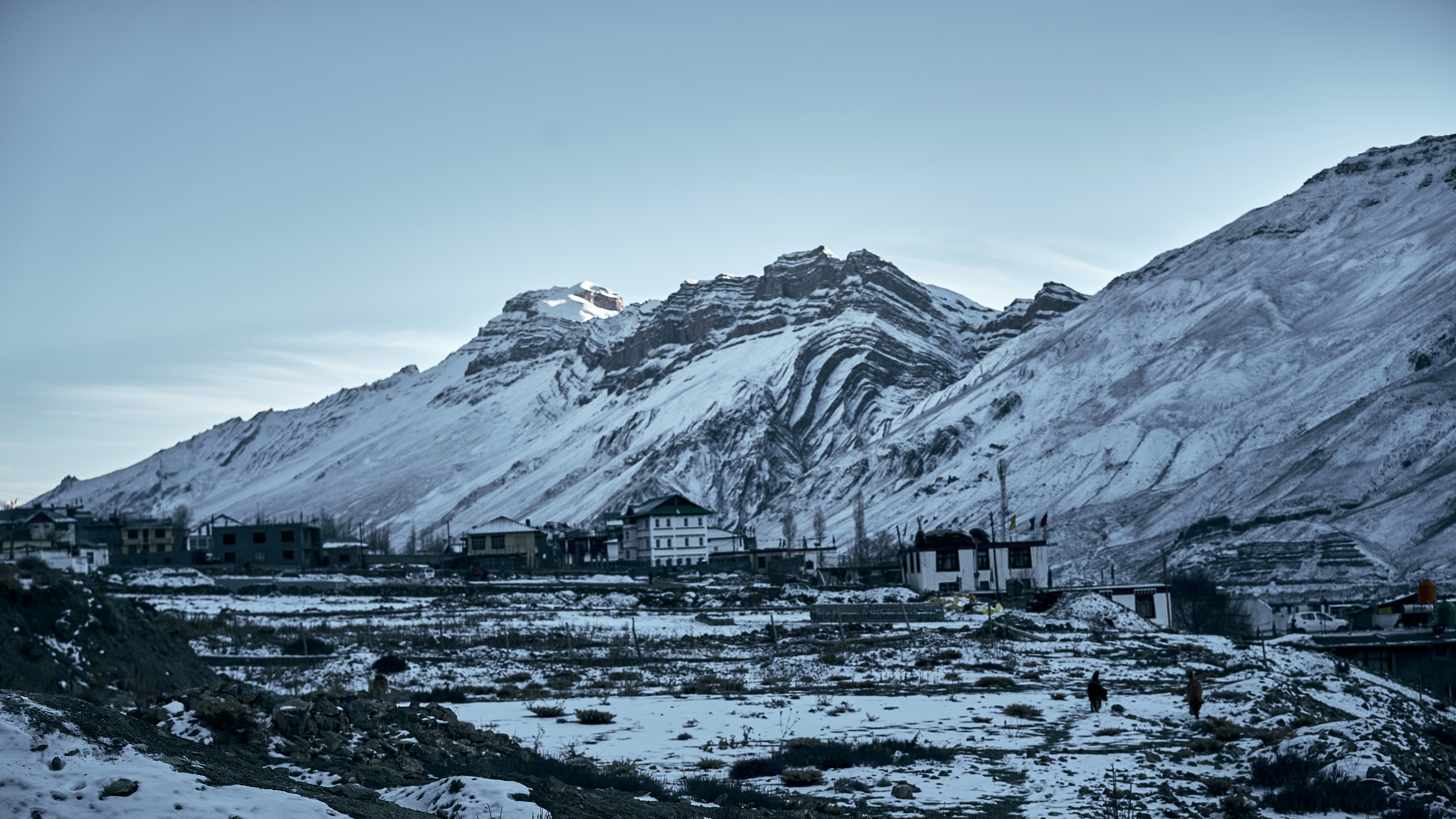 Snowy mountains with folded rock strata above a small village in a valley
