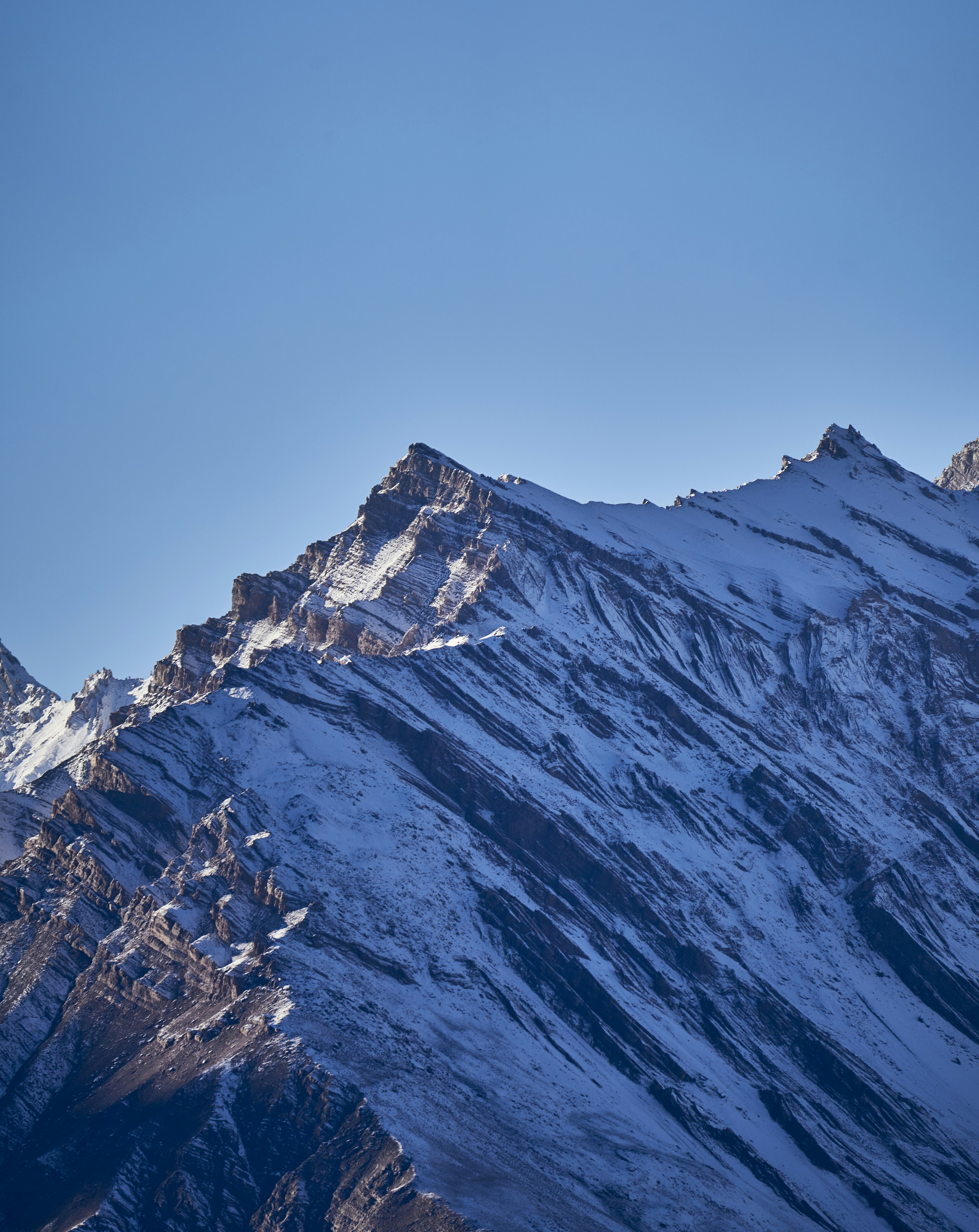 Snow covered mountain peaks against a clear blue sky