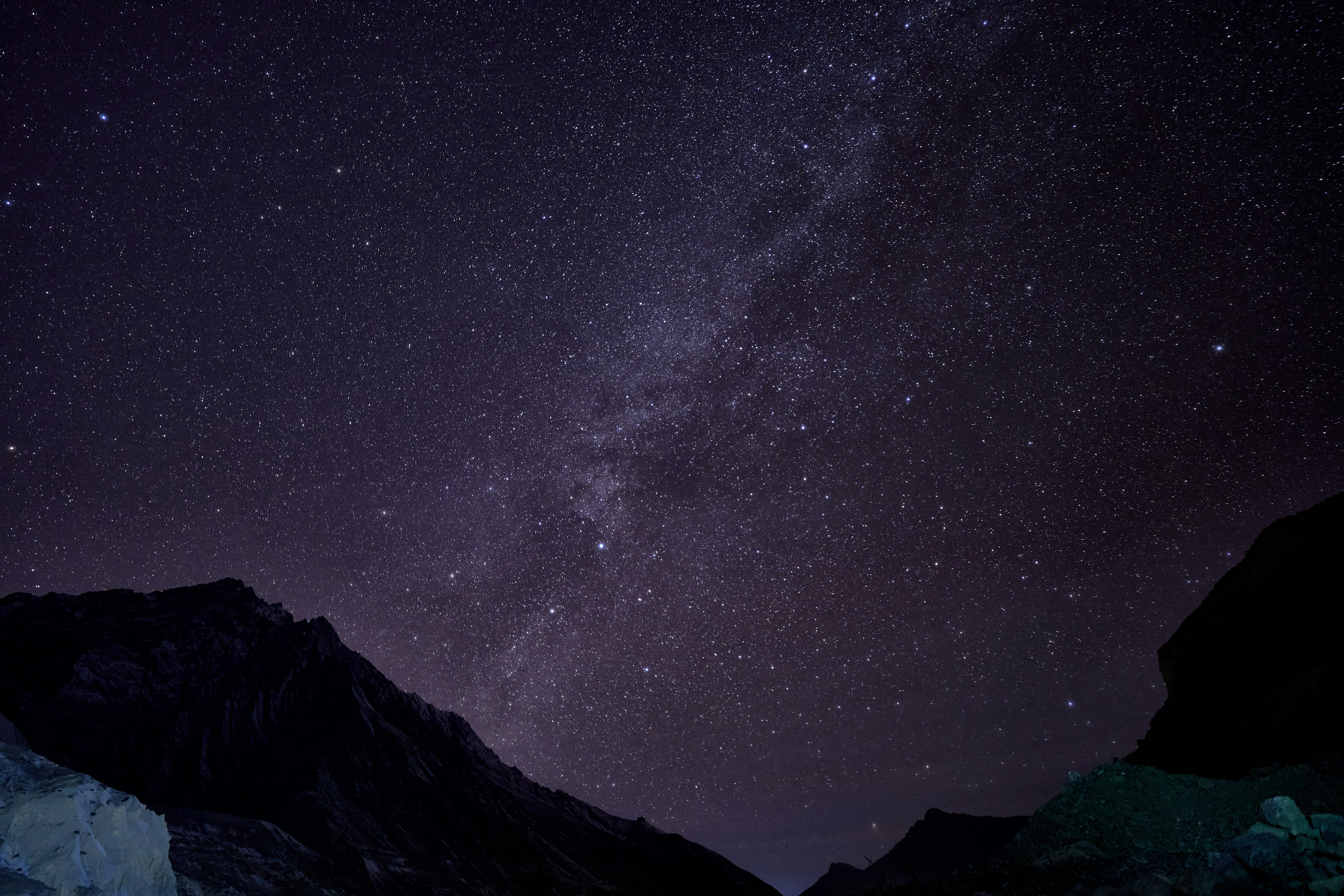 The Milky Way galaxy stretching across a dark night sky above mountain silhouettes