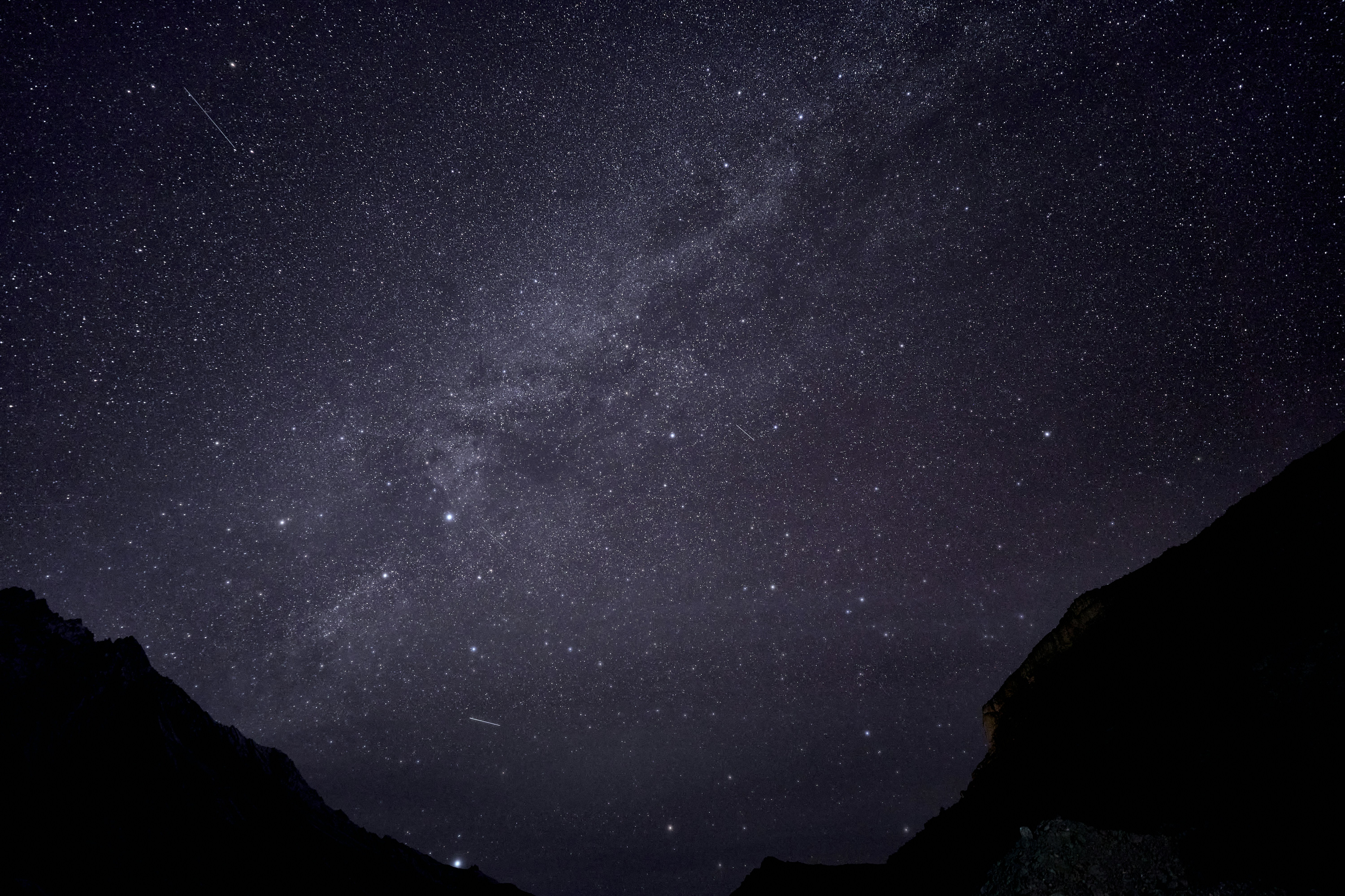 A dense field of stars and the Milky Way above dark mountain silhouettes