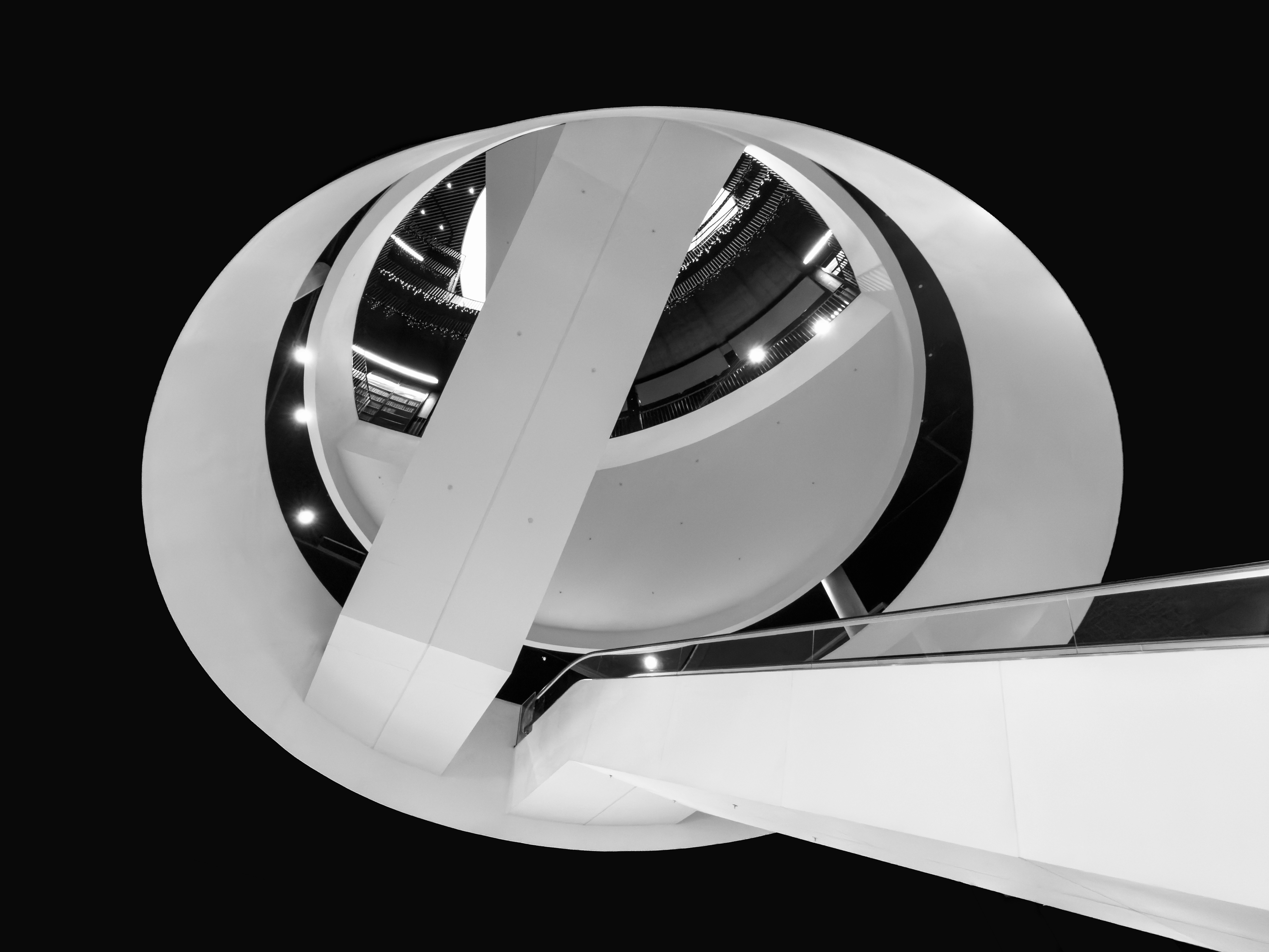 A black and white view looking up at a curved white architectural structure