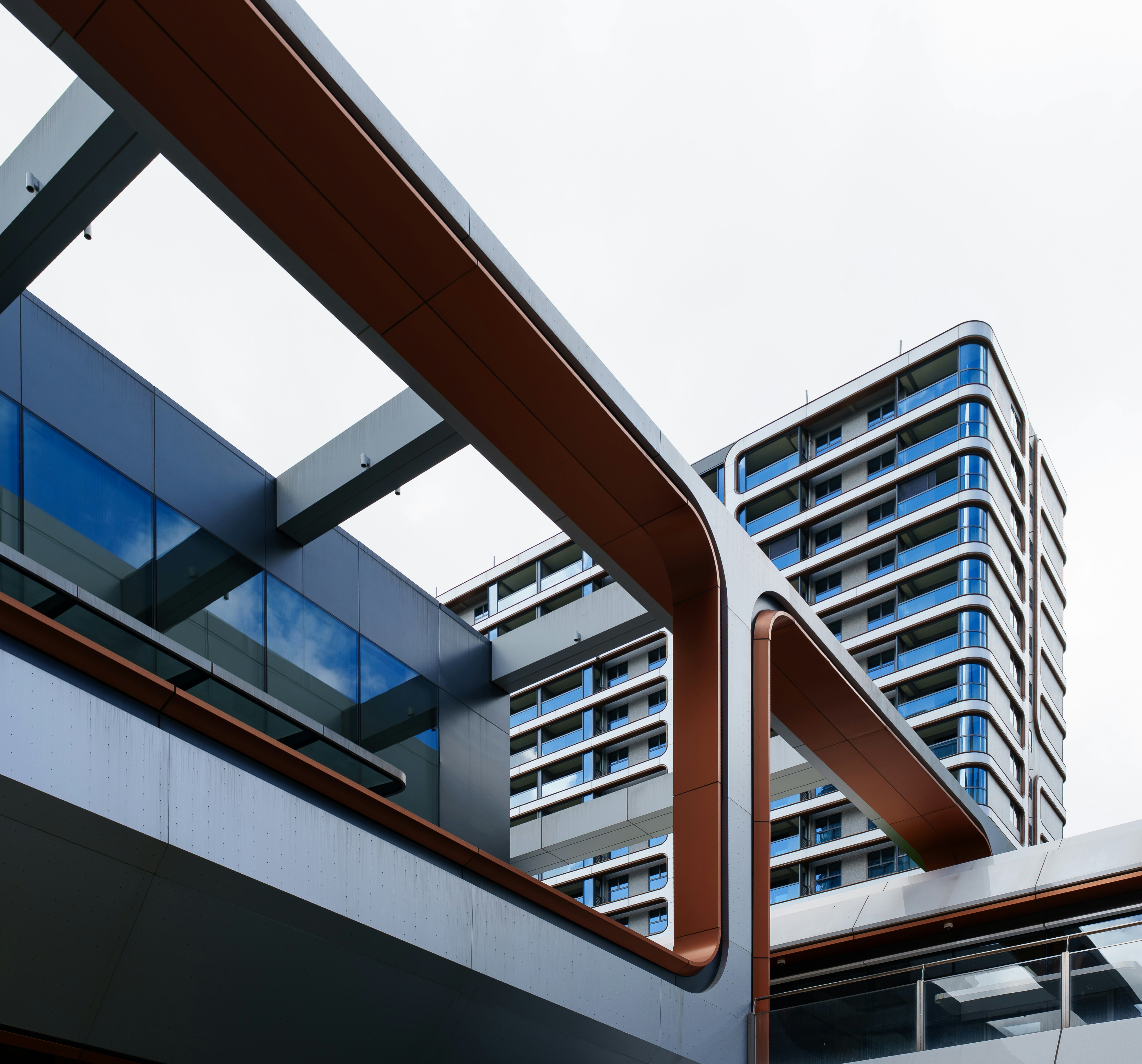 Modern apartment building with copper accents and glass balconies against a white sky