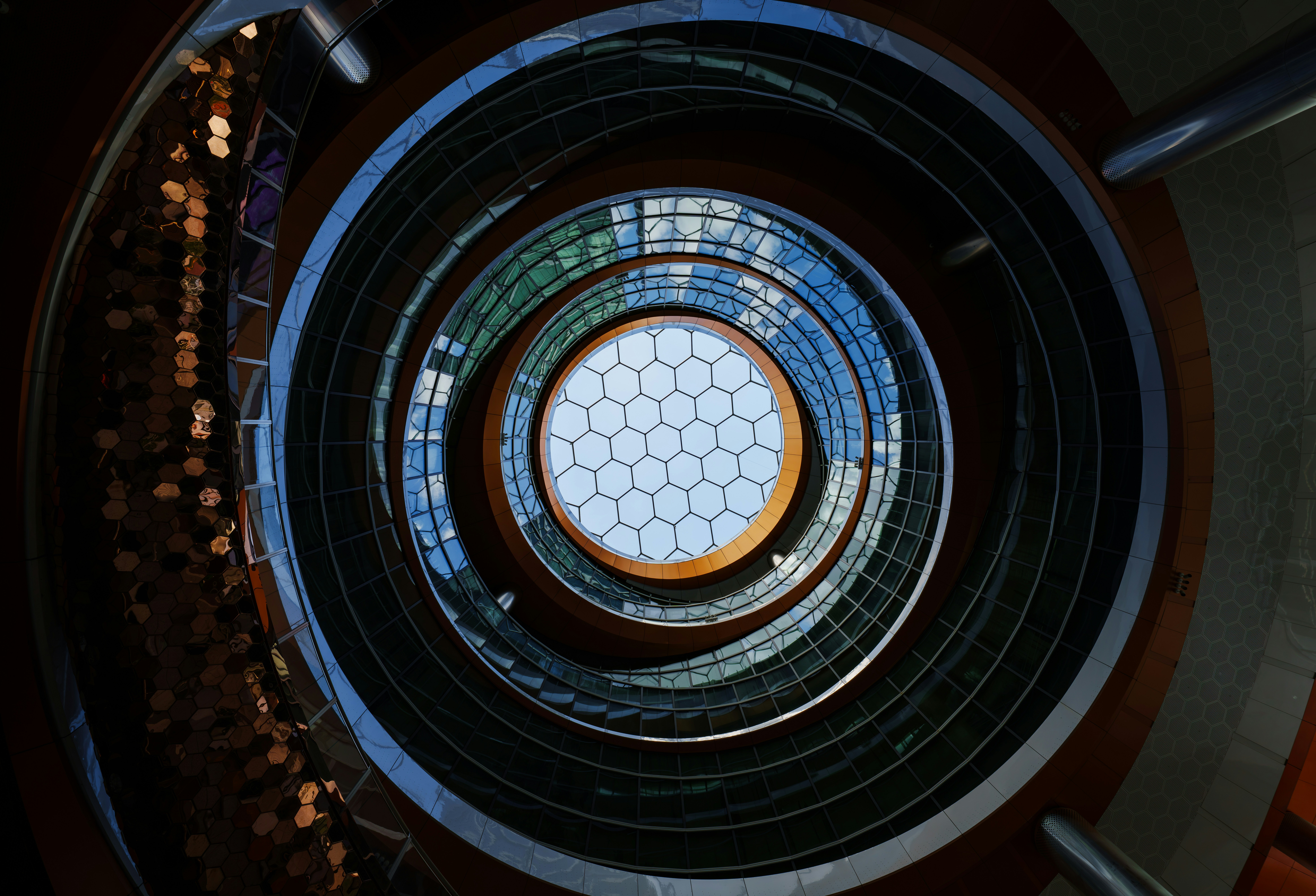 A circular atrium with a hexagonal glass skylight looking up at the sky