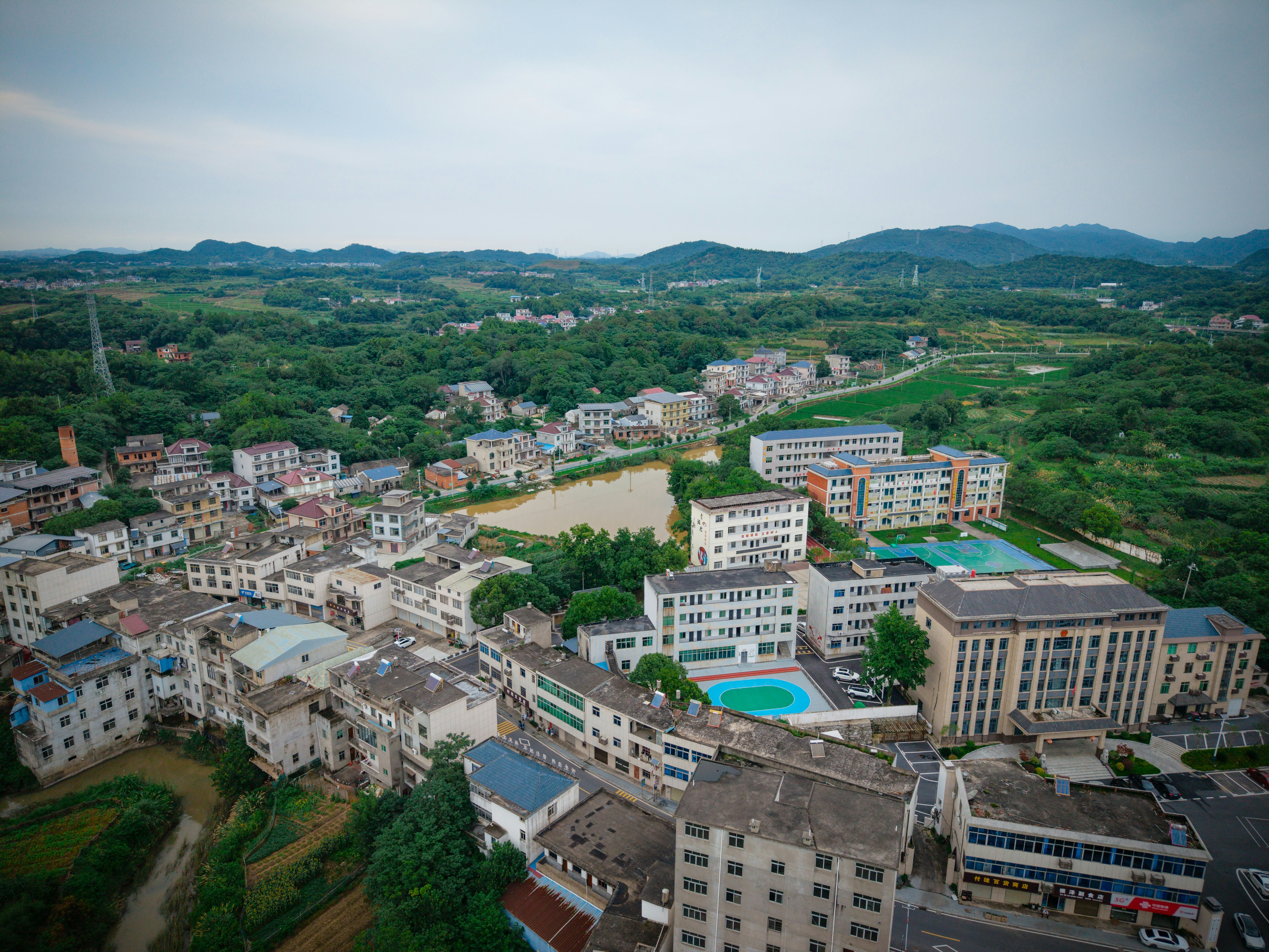 Aerial view of a rural town with school buildings and a pond