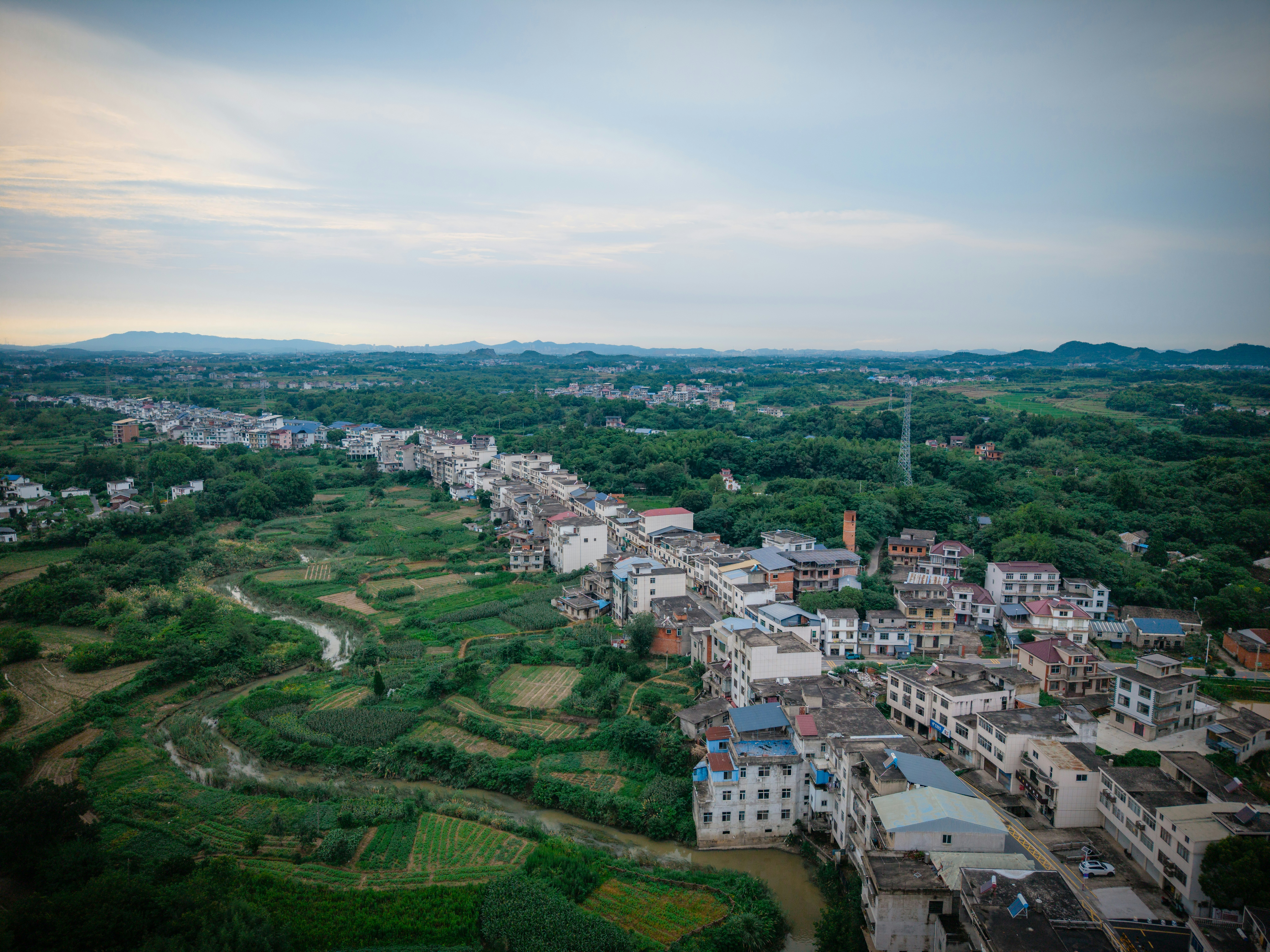 Aerial view of a village with white buildings along a winding river and fields