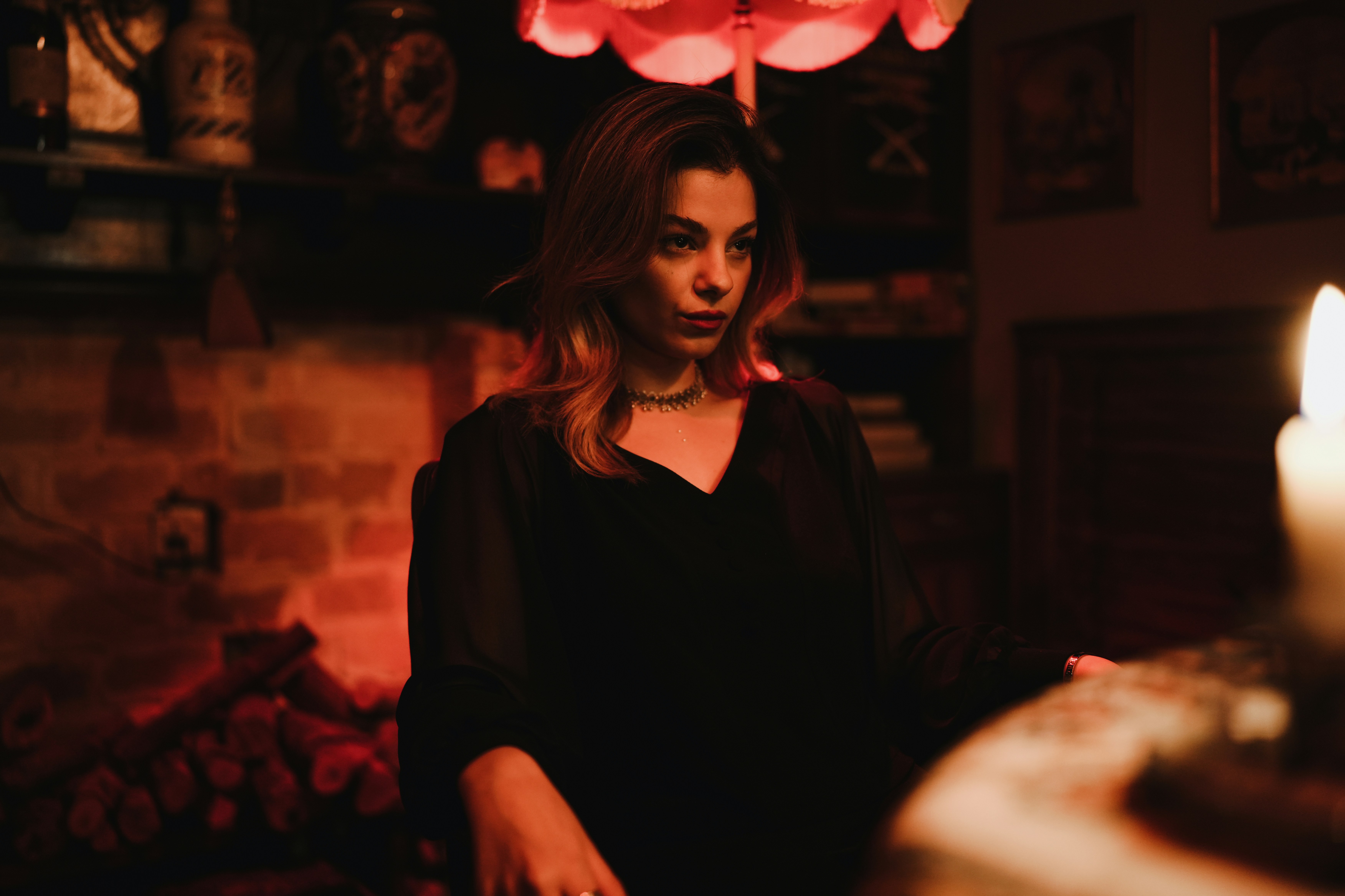A woman in a black blouse sitting by candlelight in a dimly lit room