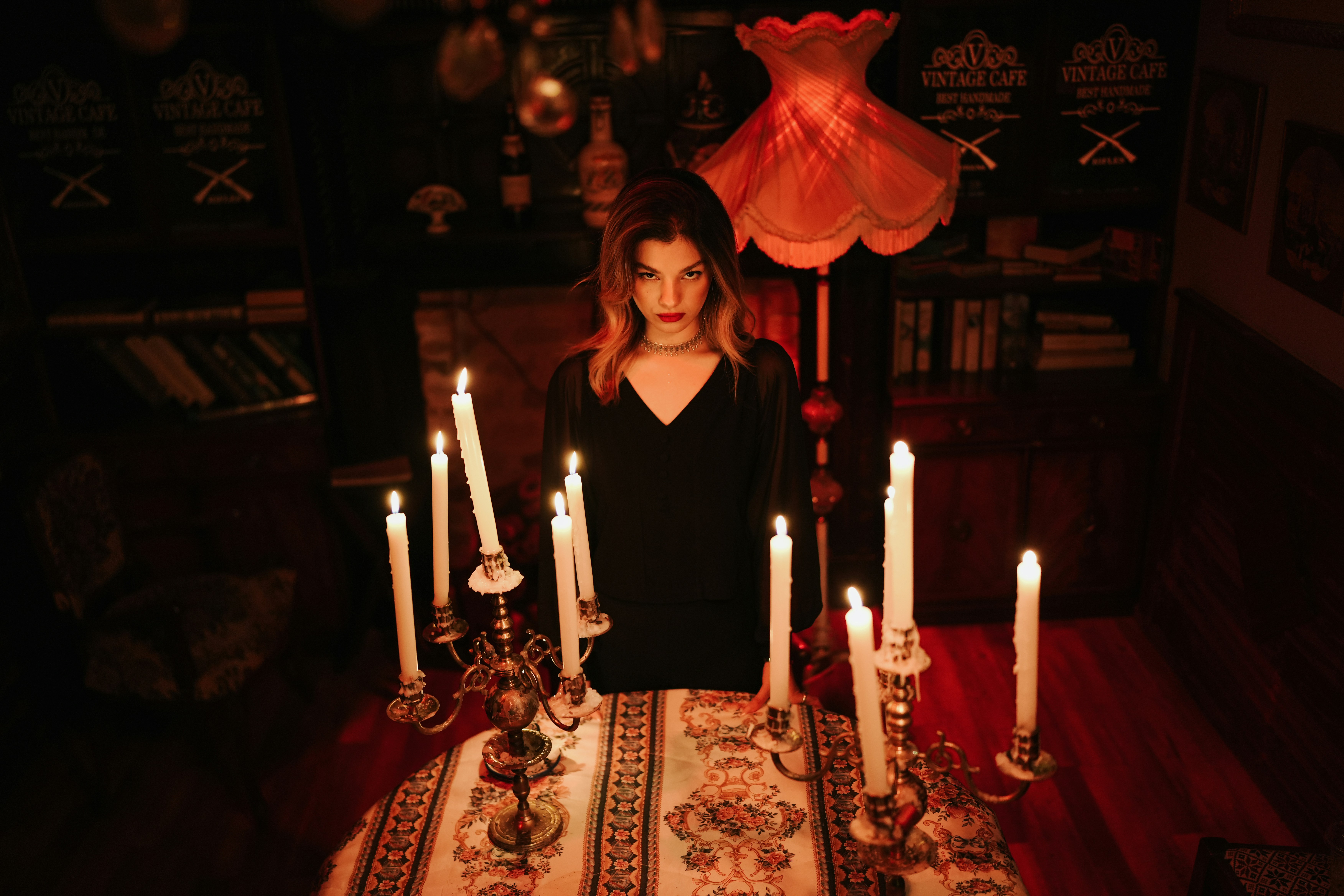 A woman in a black dress behind a table with lit candles in candelabras