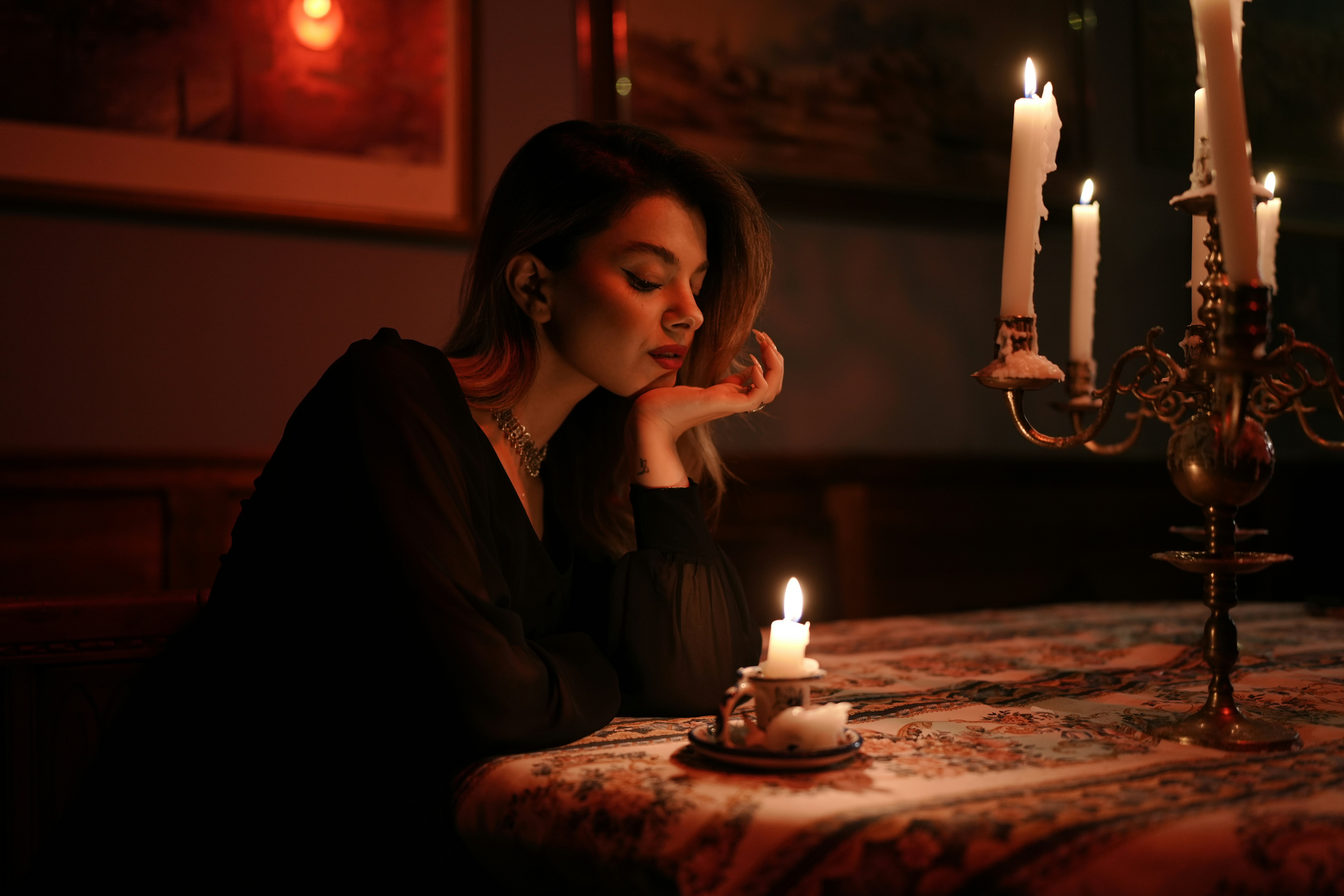 A woman in a black dress at a table with lit candles
