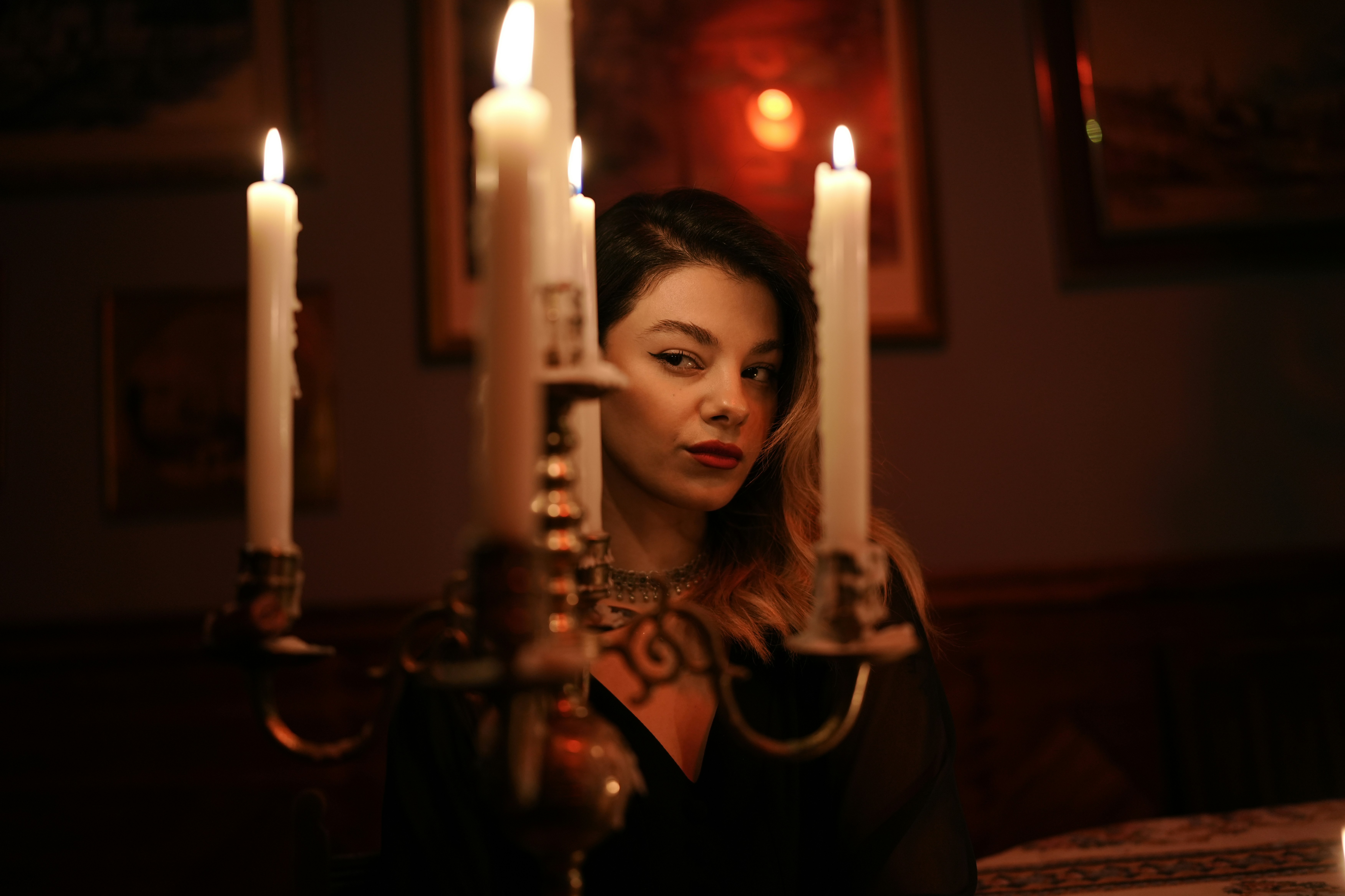 A woman behind a lit candelabra in a dimly lit room