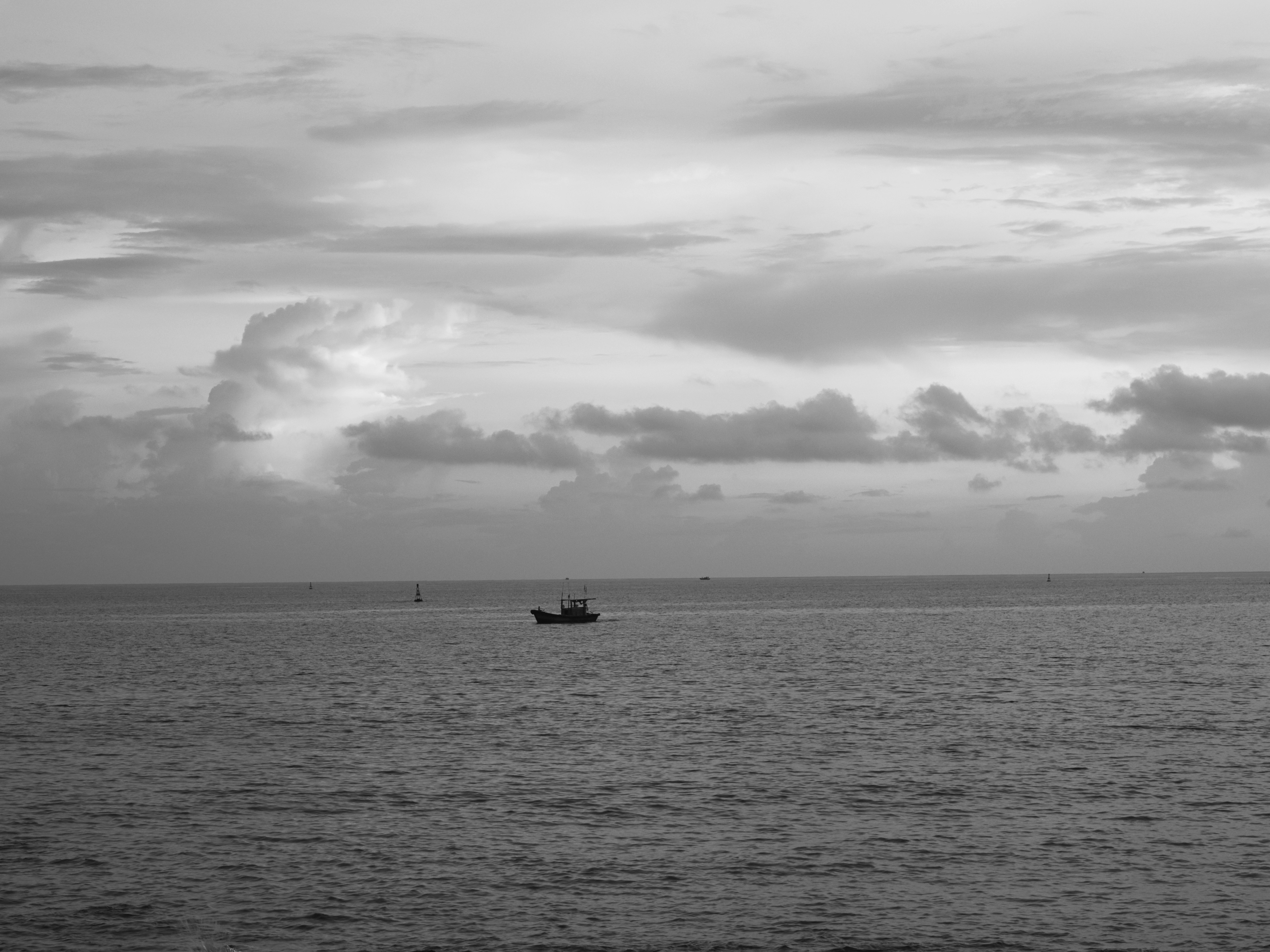 Una piccola barca da pesca su un mare calmo sotto un cielo nuvoloso