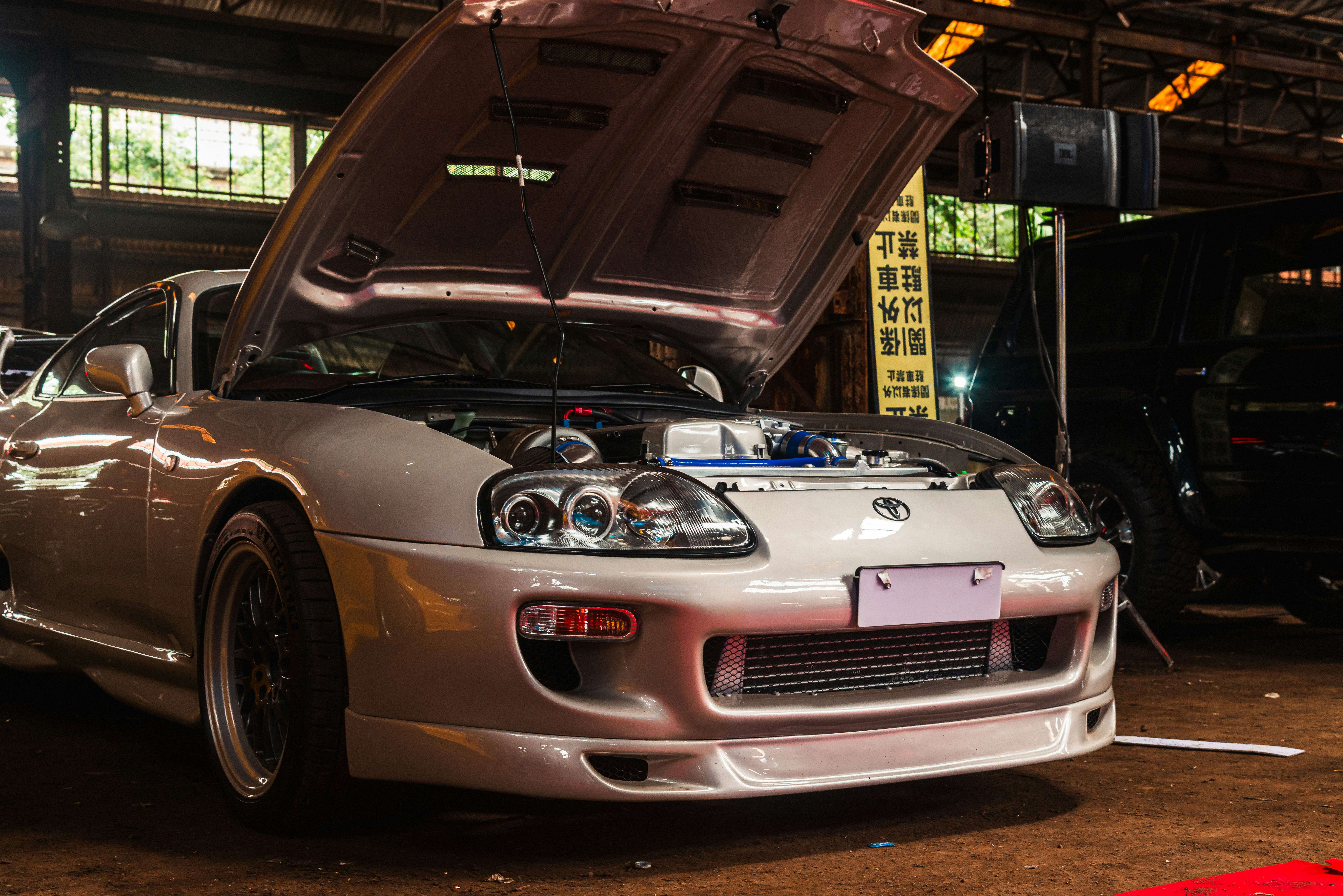 A silver fourth-generation Toyota Supra (MK4/A80) with its hood open at a car exhibition in Mumbai, India.