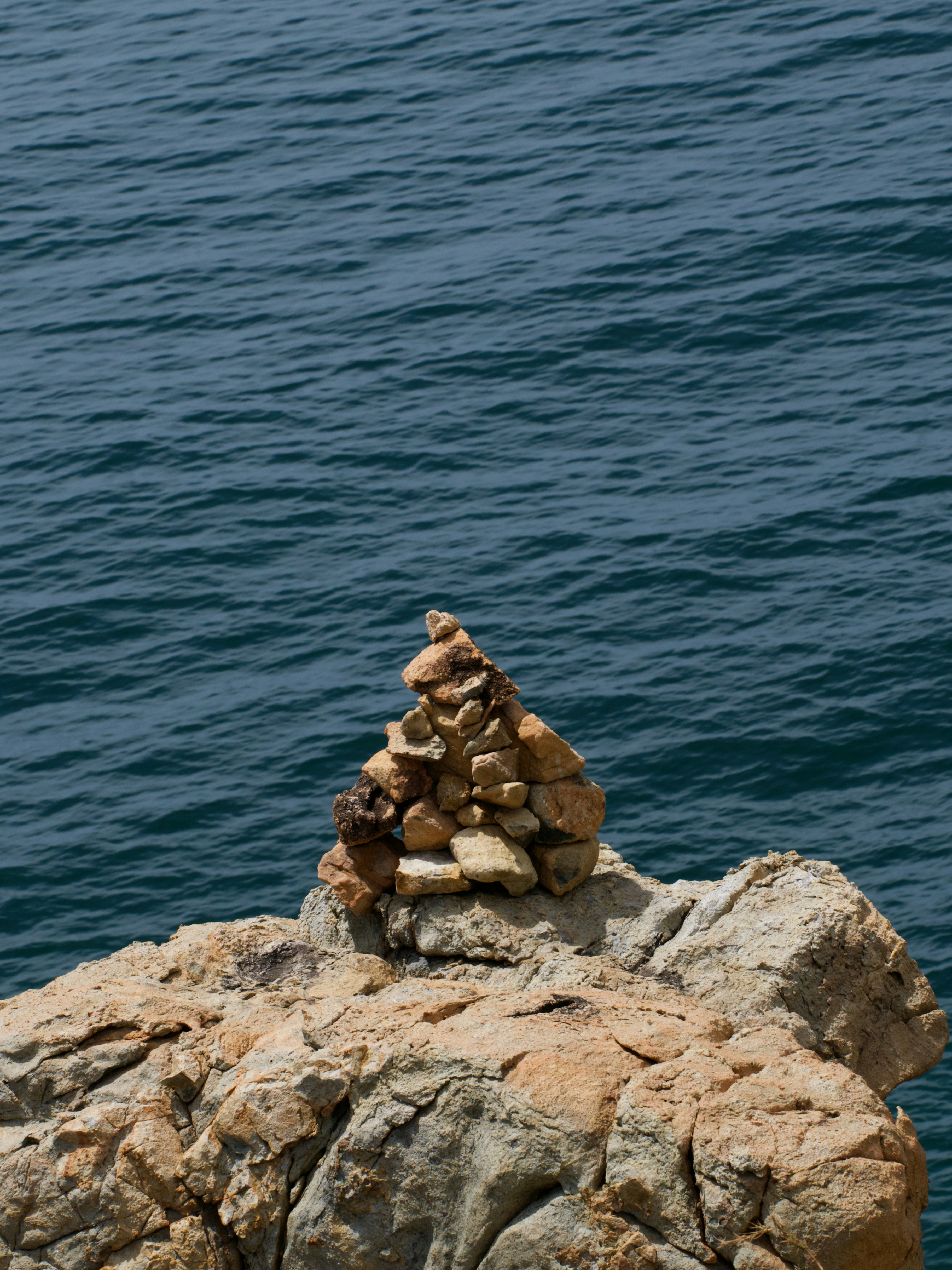 Un piccolo mucchio di pietre equilibrate su una scogliera rocciosa sopra l'acqua scura