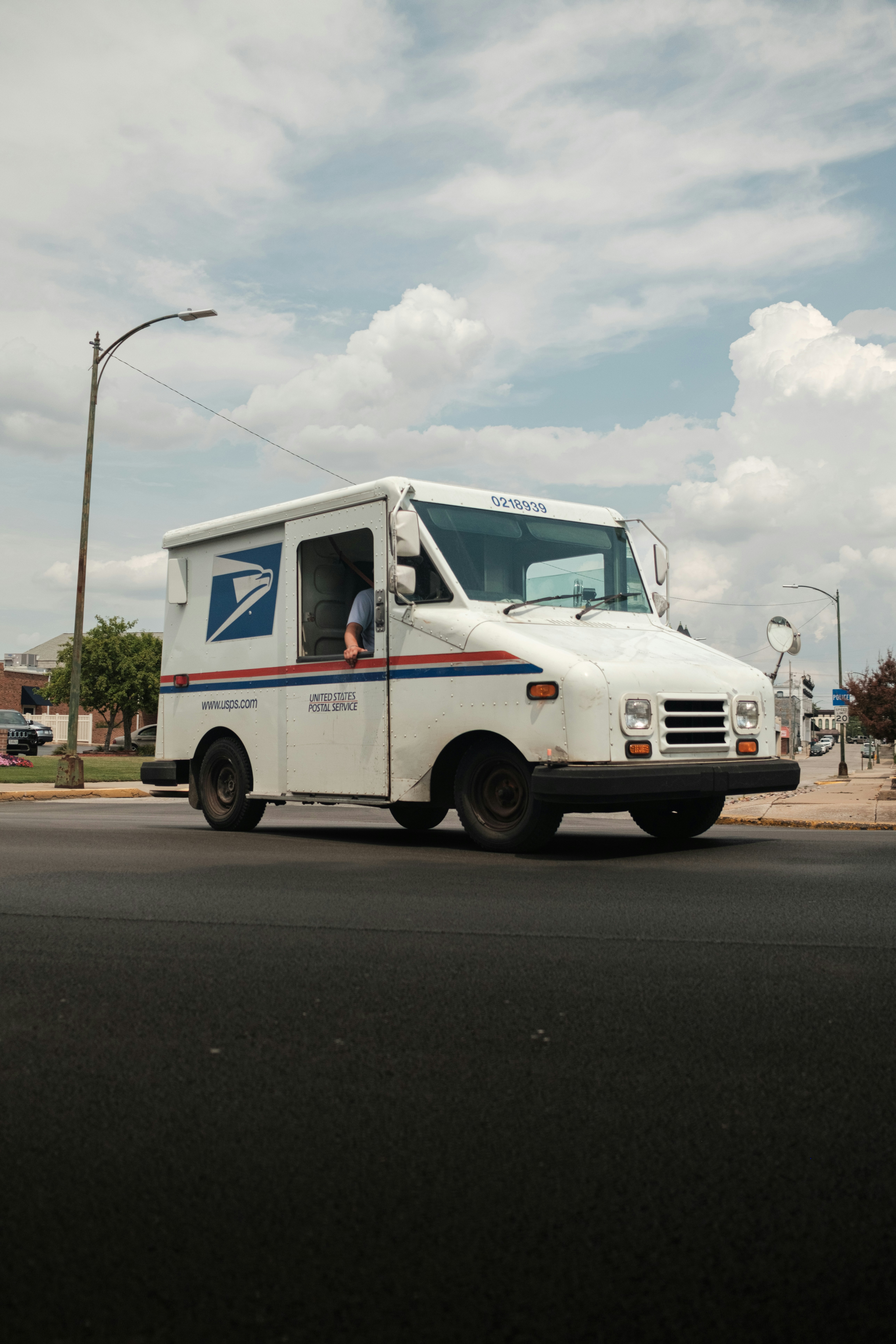 A white United States Postal Service mail truck driving on a city street