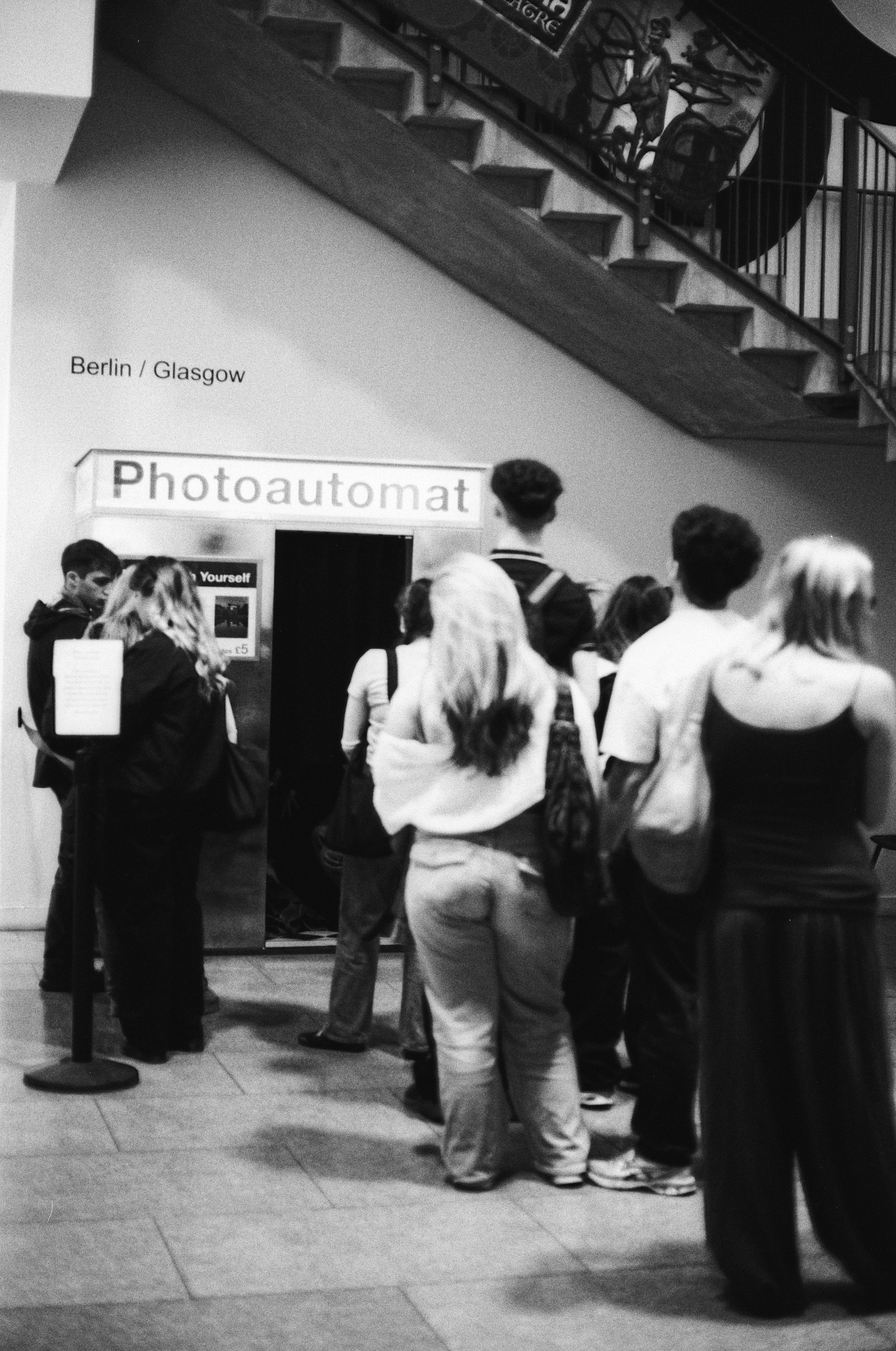 A group of people waiting in a line for a Photoautomat booth