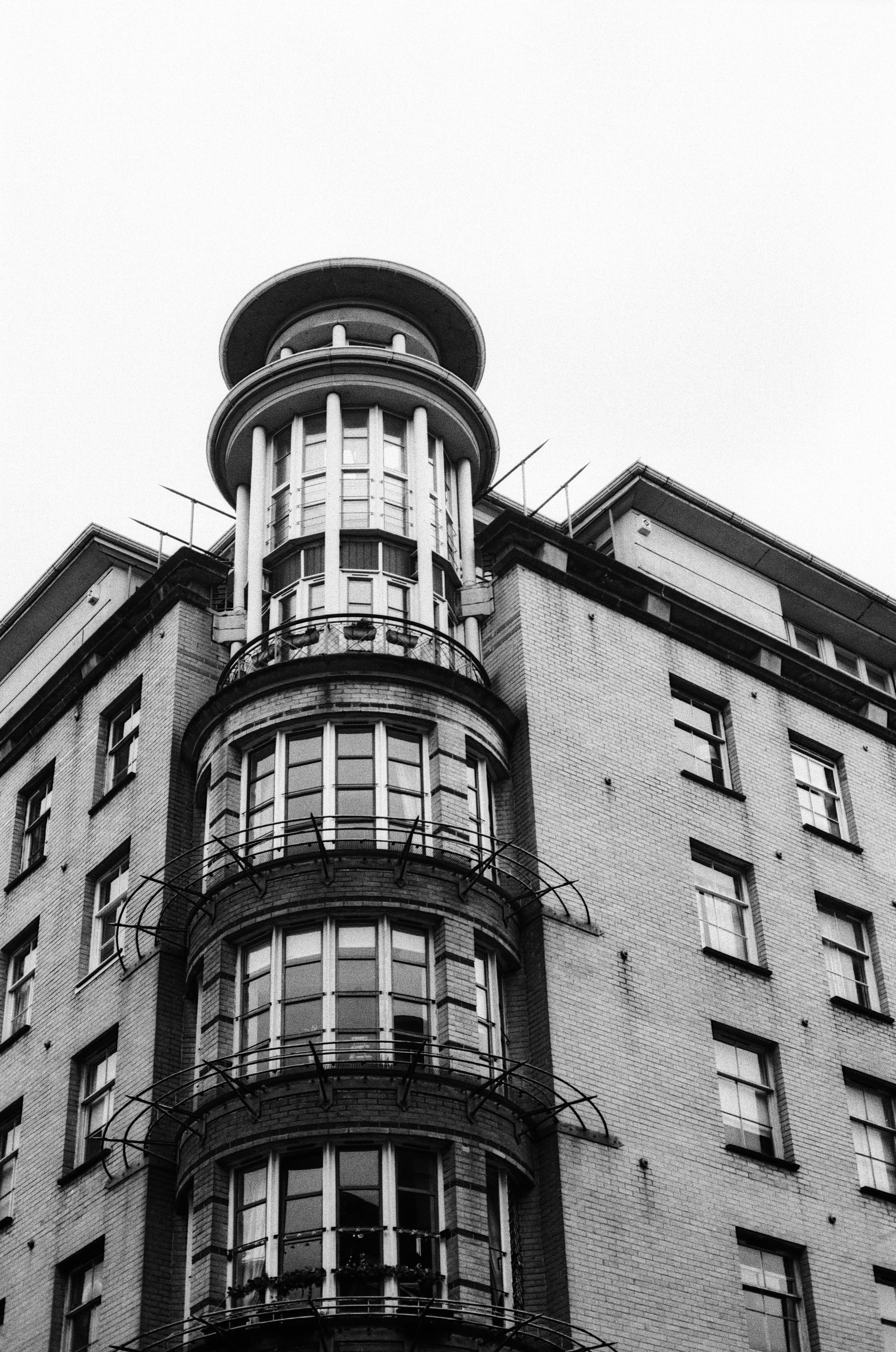 A black and white view of a brick building with a curved corner tower