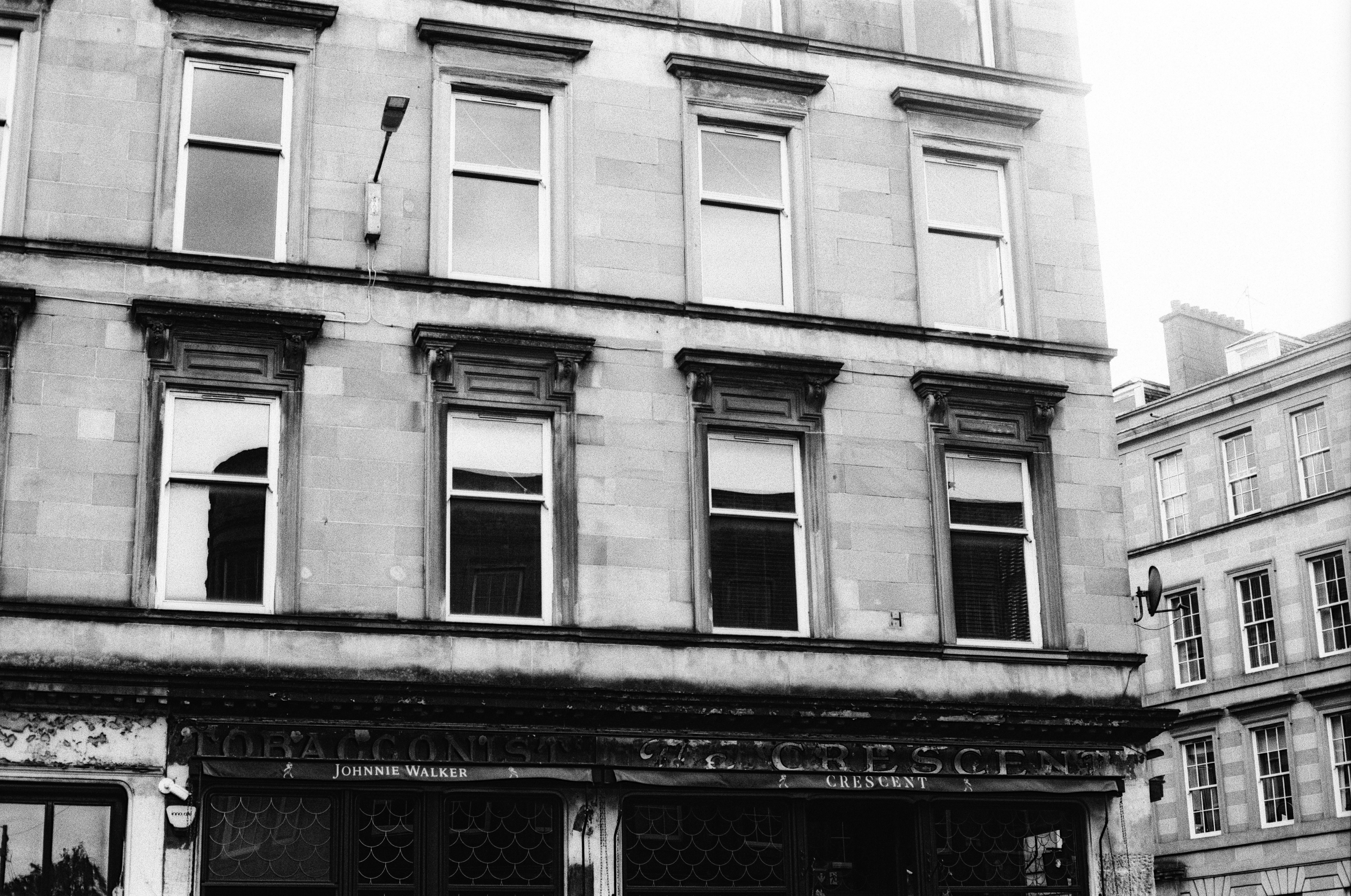 A stone building facade with multiple windows above a storefront in black and white